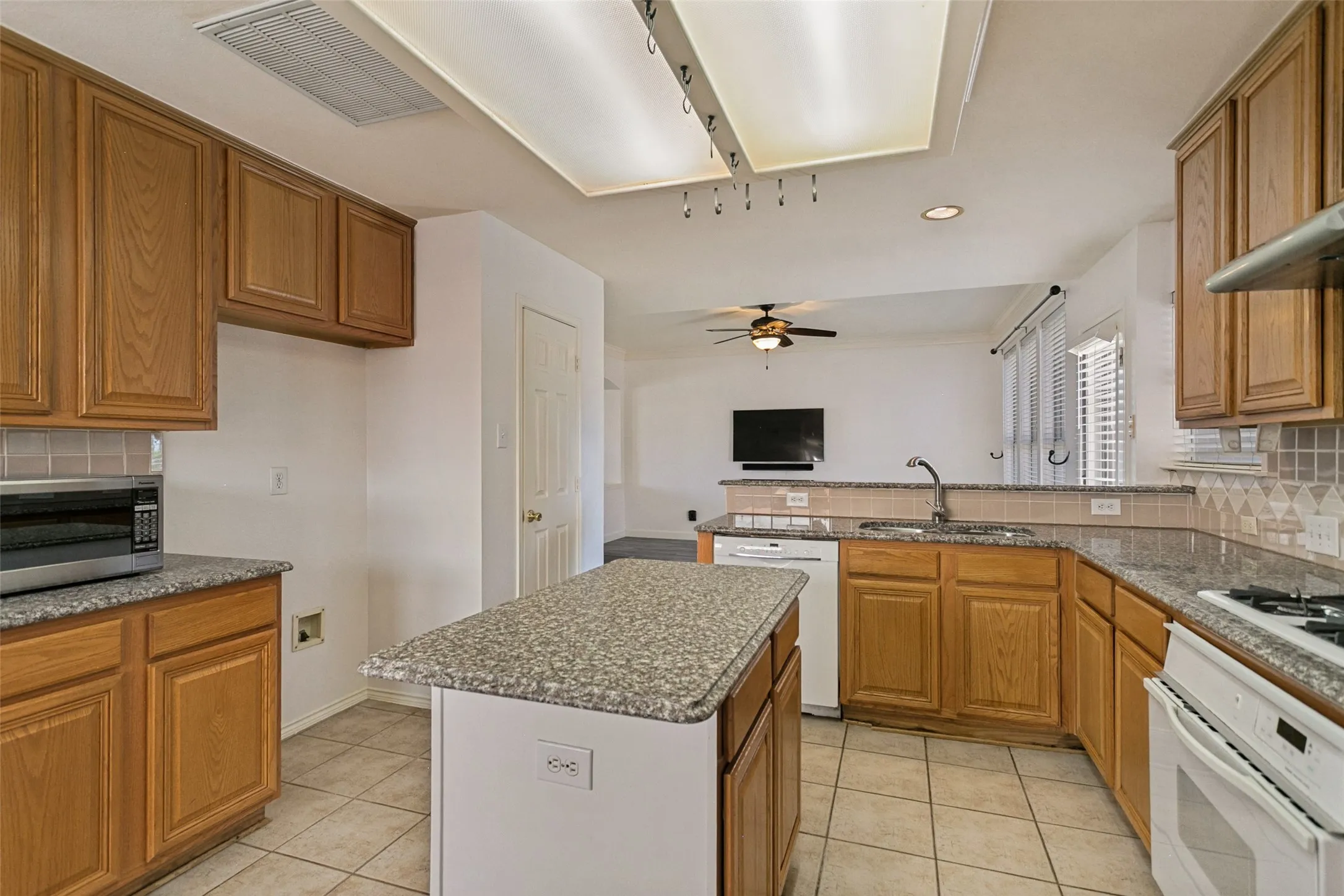 Kitchen featuring wood cabinetry, granite-style countertops, tile flooring, and a center island
