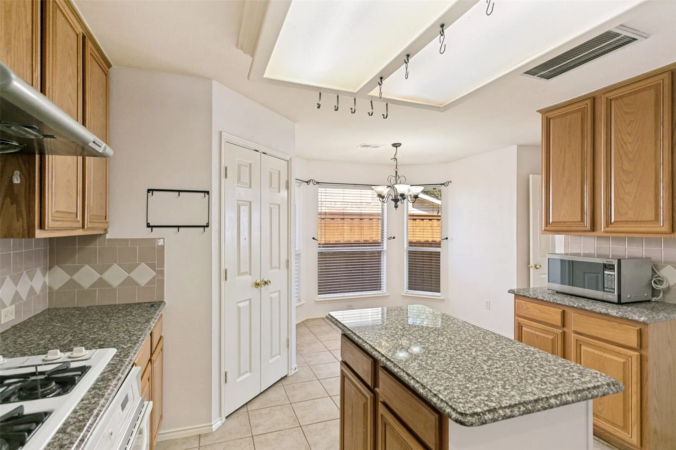 Kitchen featuring wood cabinetry, granite-style countertops, and a tiled backsplash