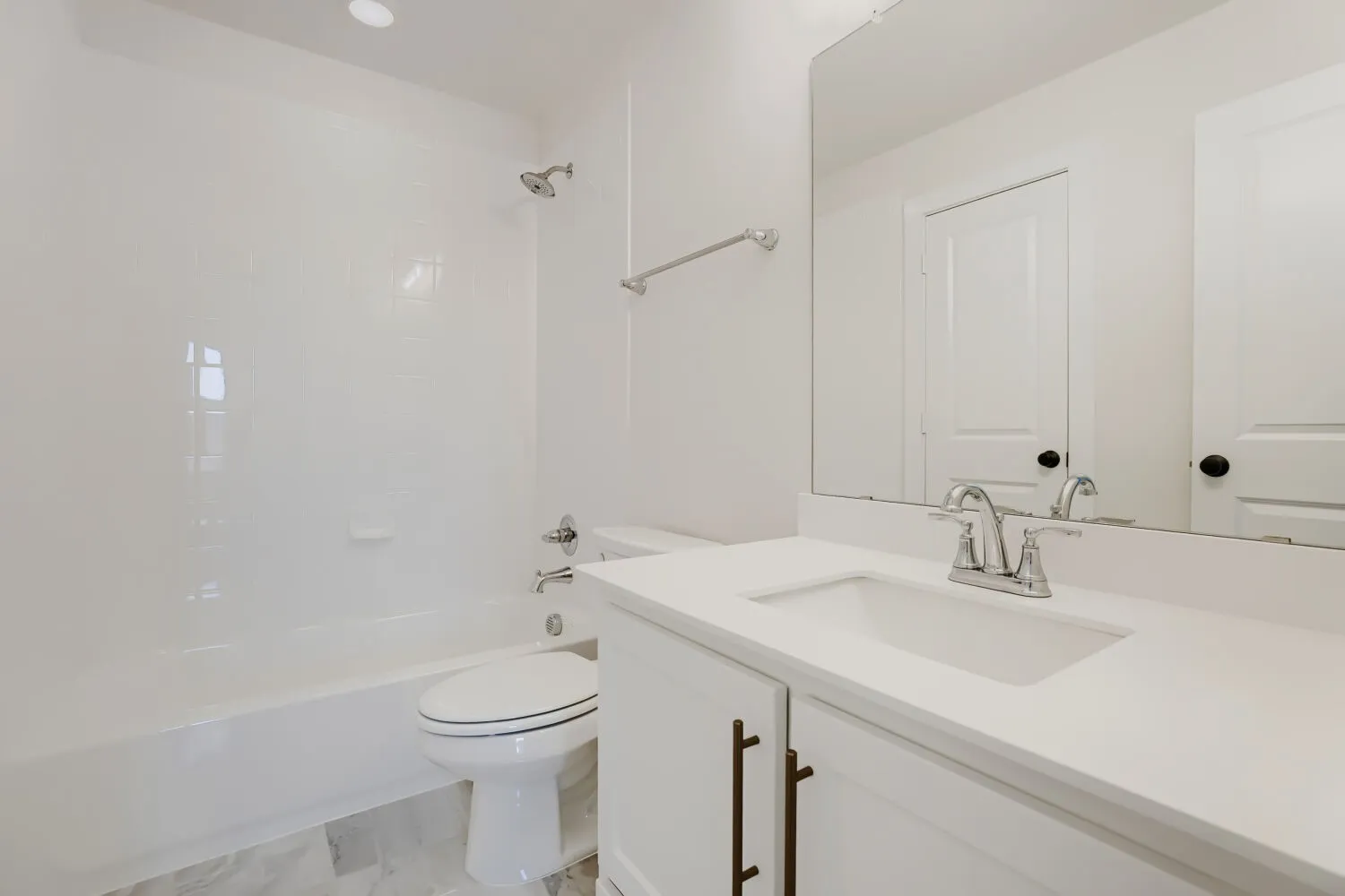 White bathtub with shower, vanity with integrated sink, chrome fixtures, and undermount lighting