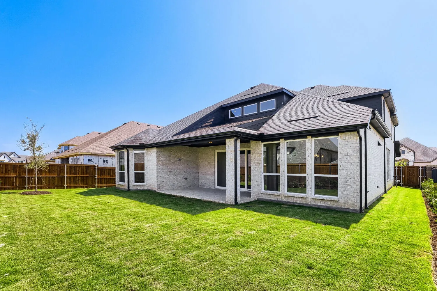 Expansive backyard featuring a manicured lawn, a covered patio, and a privacy fence