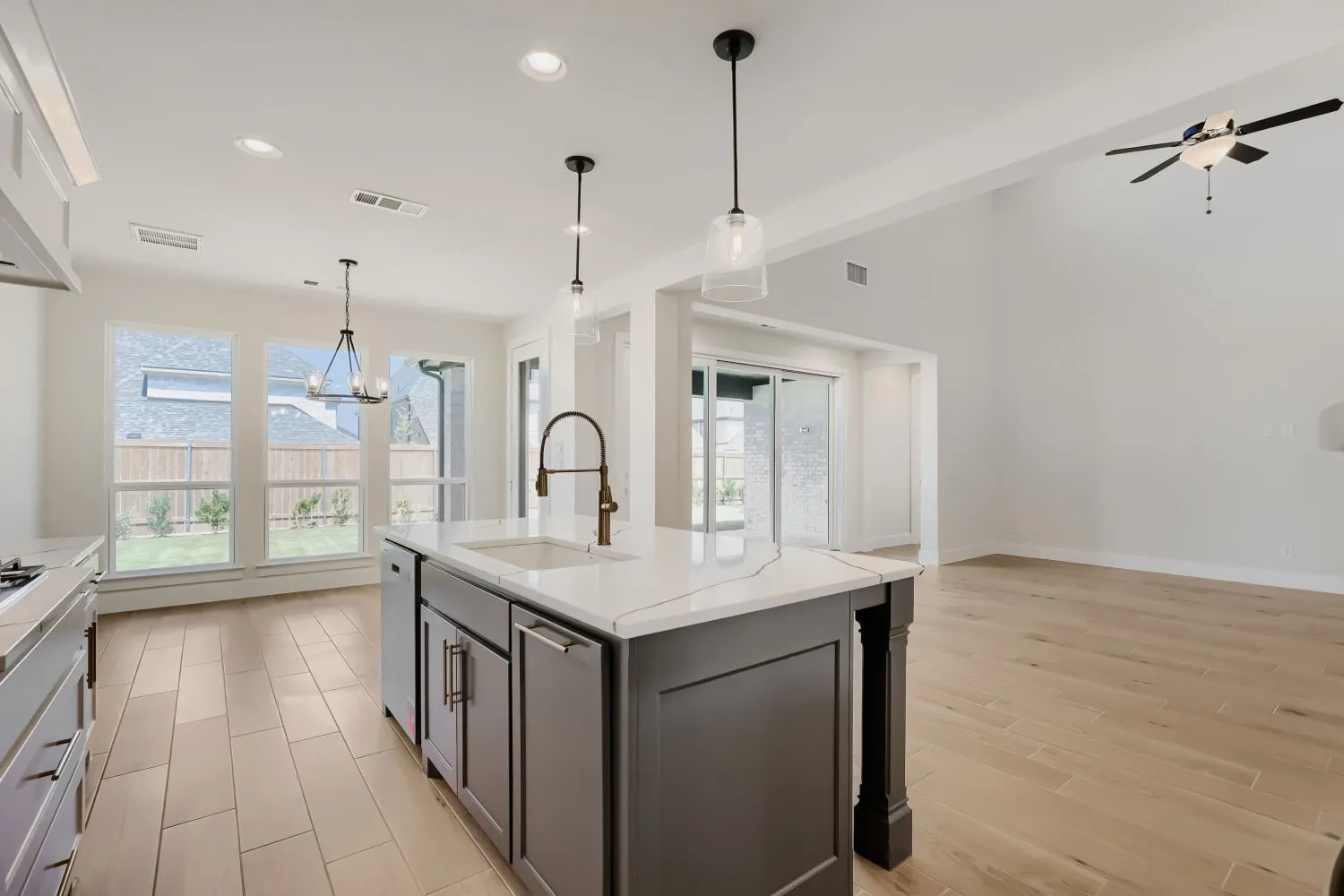 Kitchen island with a white countertop and integrated sink, stainless steel appliances, and wood-finish flooring