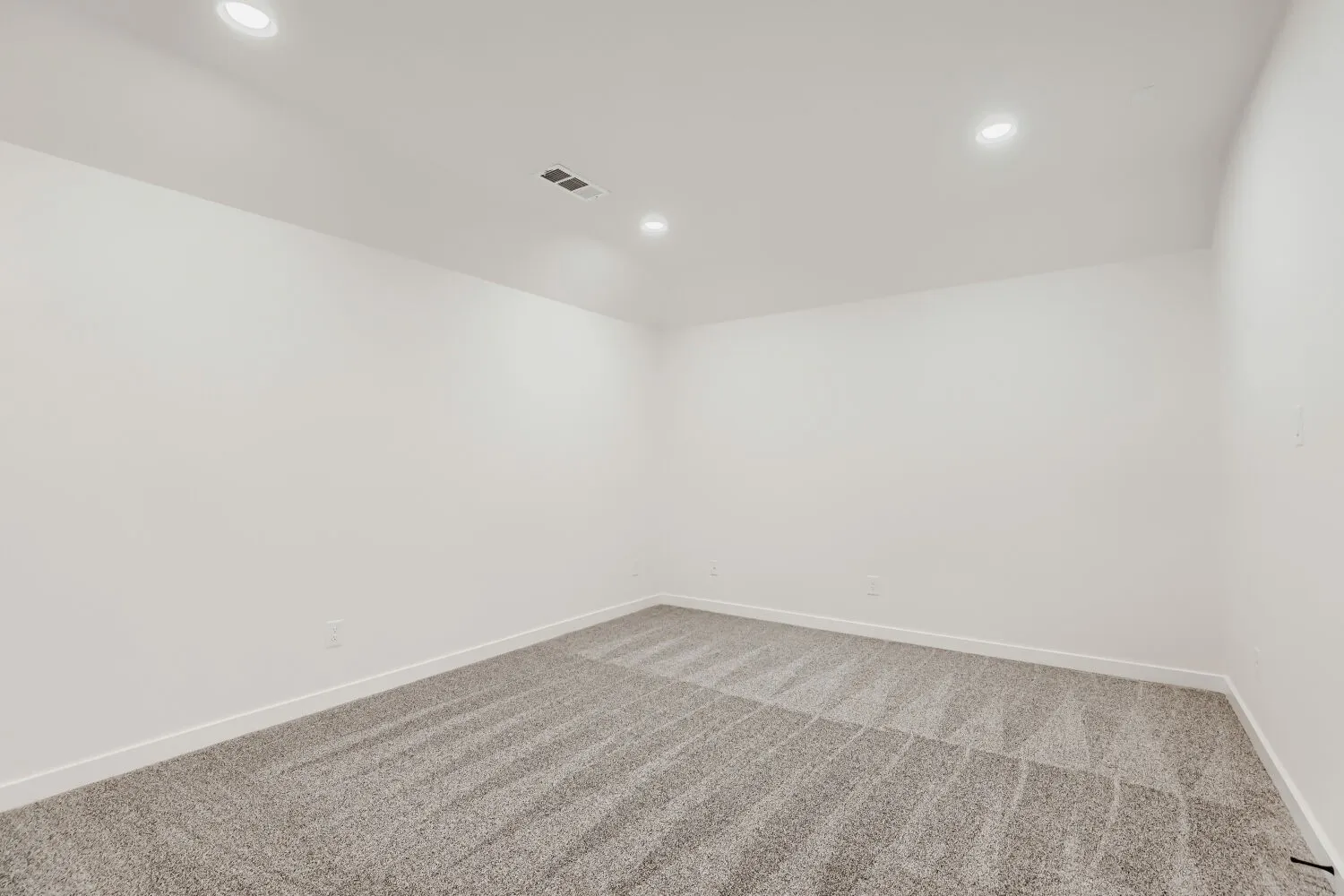 Recessed lighting, light gray carpeting, and neutral wall tones