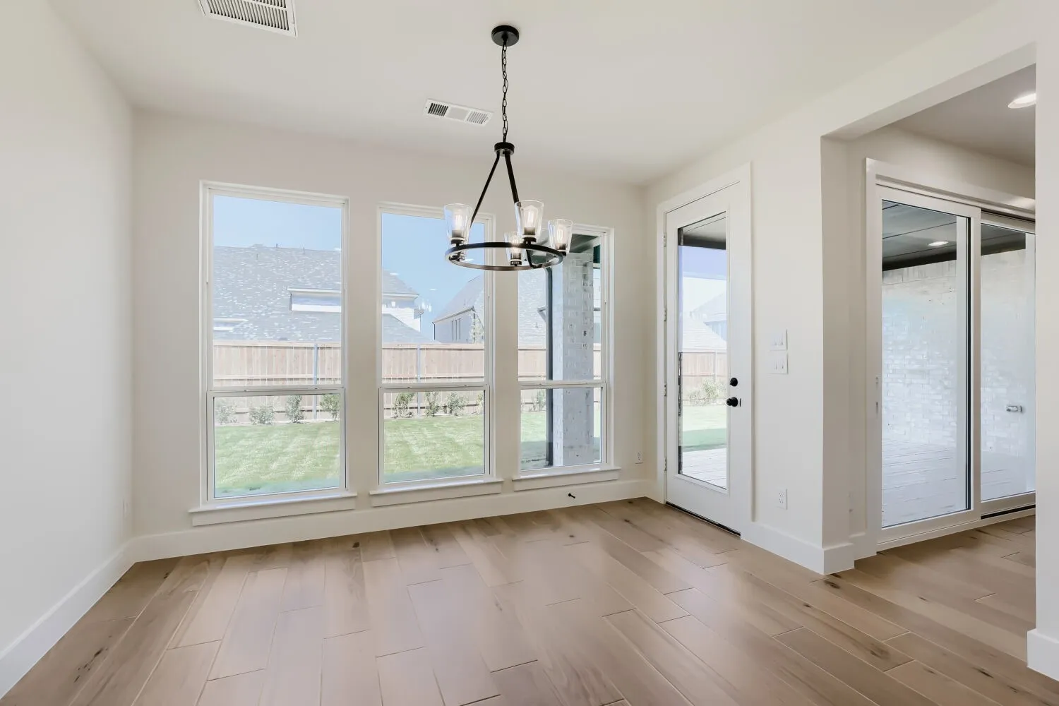 Wood-finish flooring, contemporary chandelier, multiple windows, glass-paneled door, and frosted sliding doors