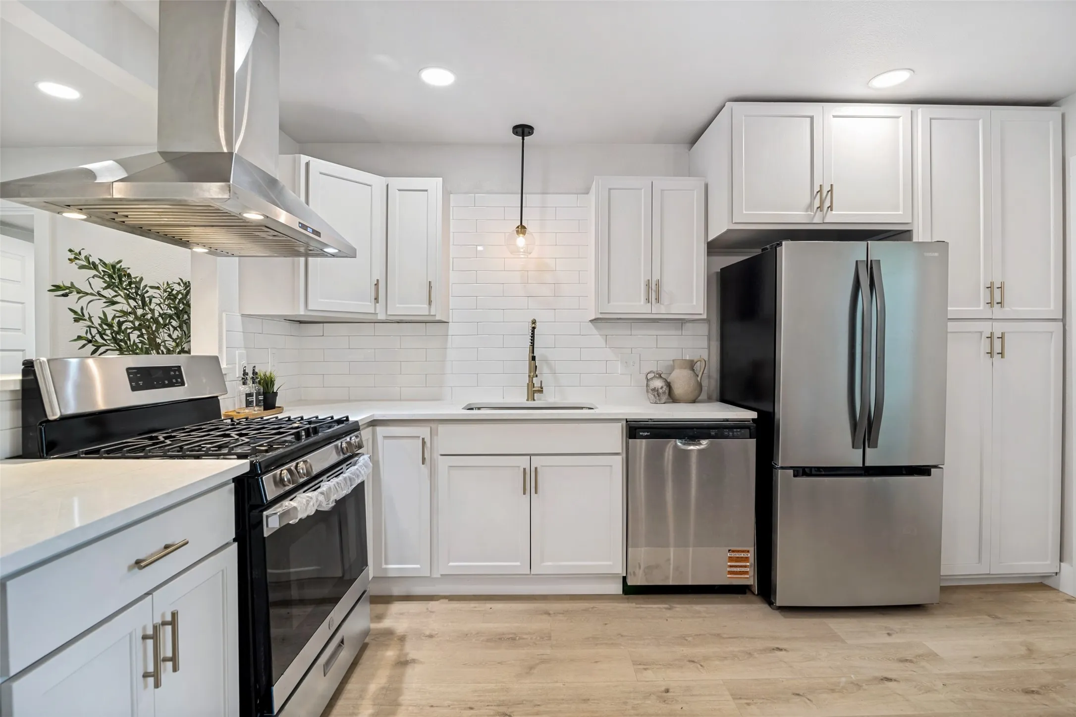 Kitchen featuring white cabinetry, stainless steel appliances, white subway tile backsplash, light-toned wood-finish flooring, and recessed lighting
