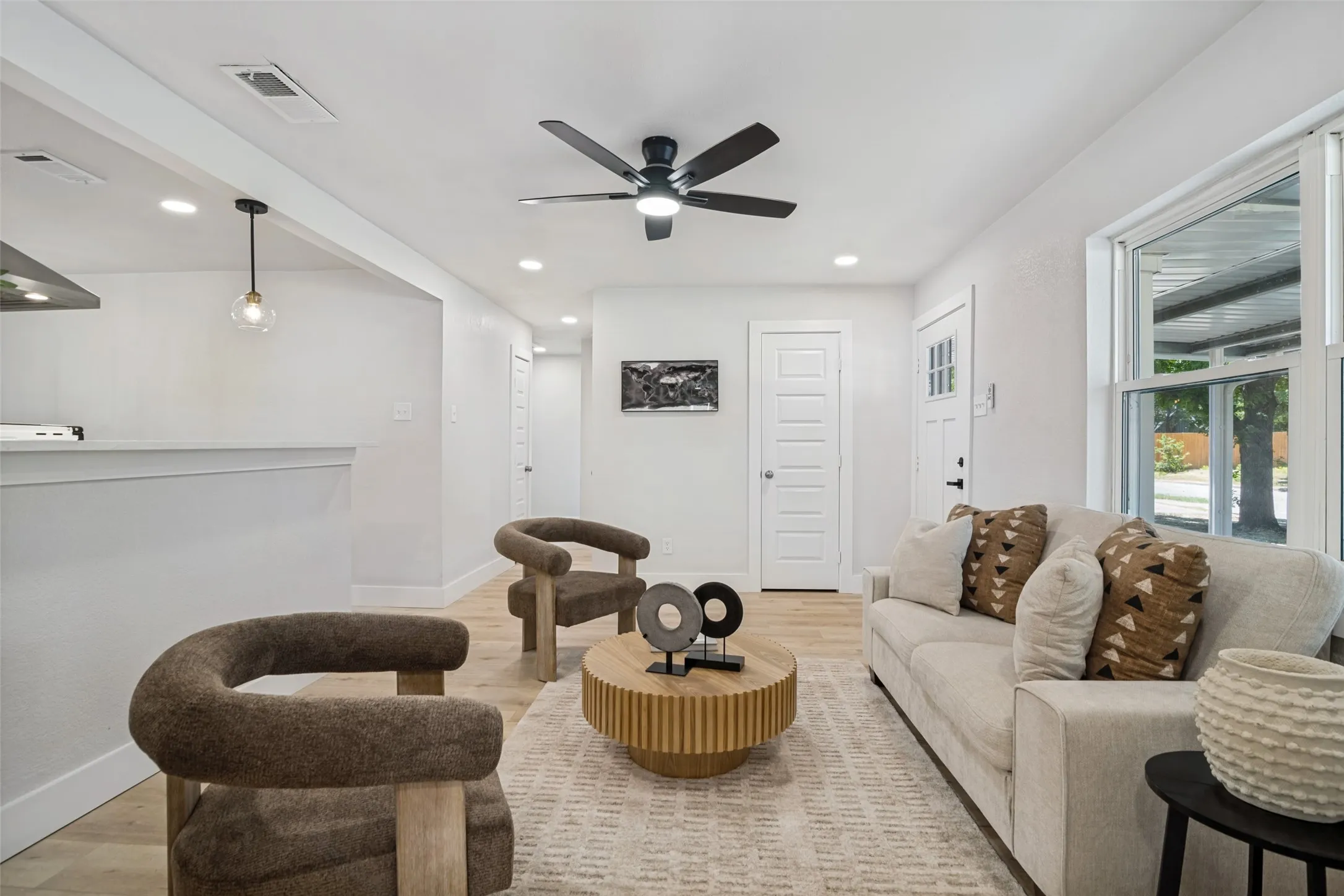 Recessed lighting, wood-finish flooring, a contemporary ceiling fan, and a transom window above the entry door