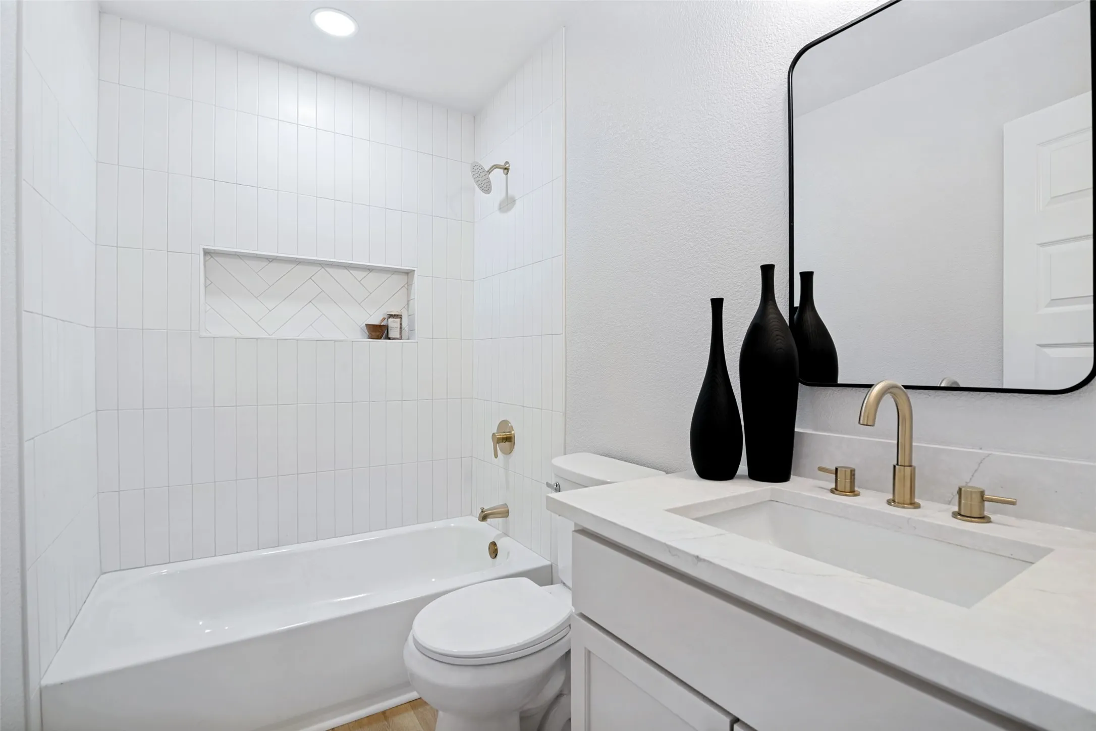 White tiled tub and shower combination with an integrated niche featuring a herringbone pattern