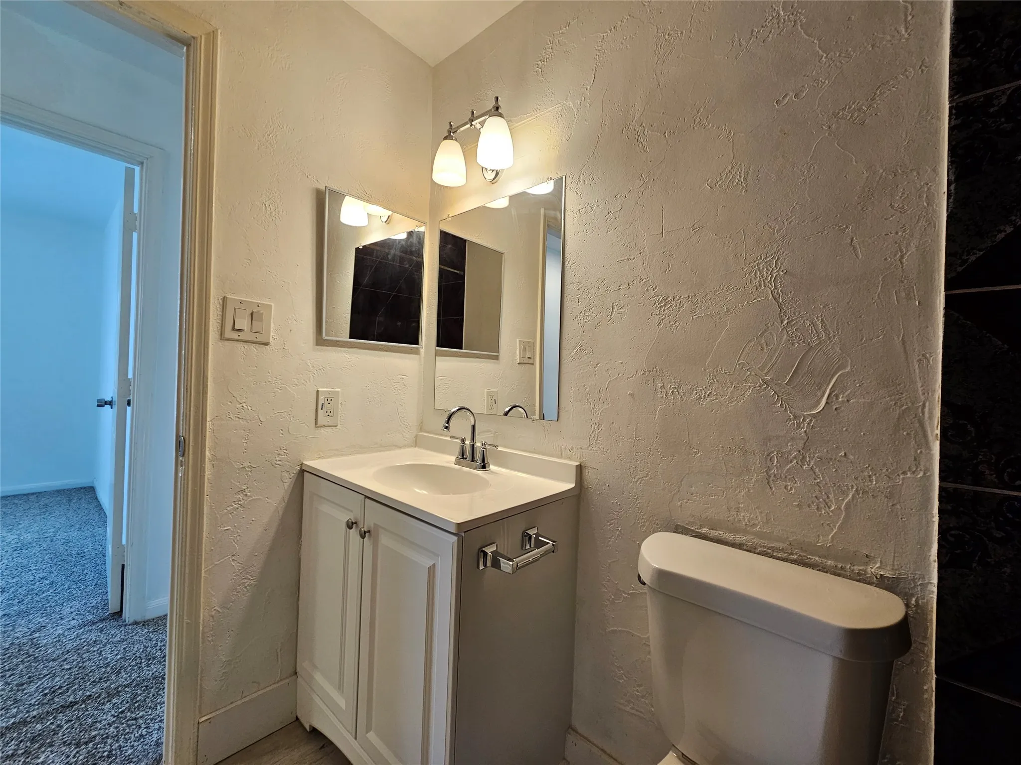 White vanity with two cabinet doors, an integrated sink, and a chrome faucet
