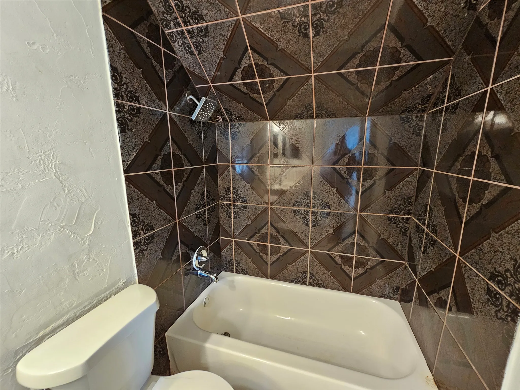 Bathtub with a shower fixture and decorative tiled surround