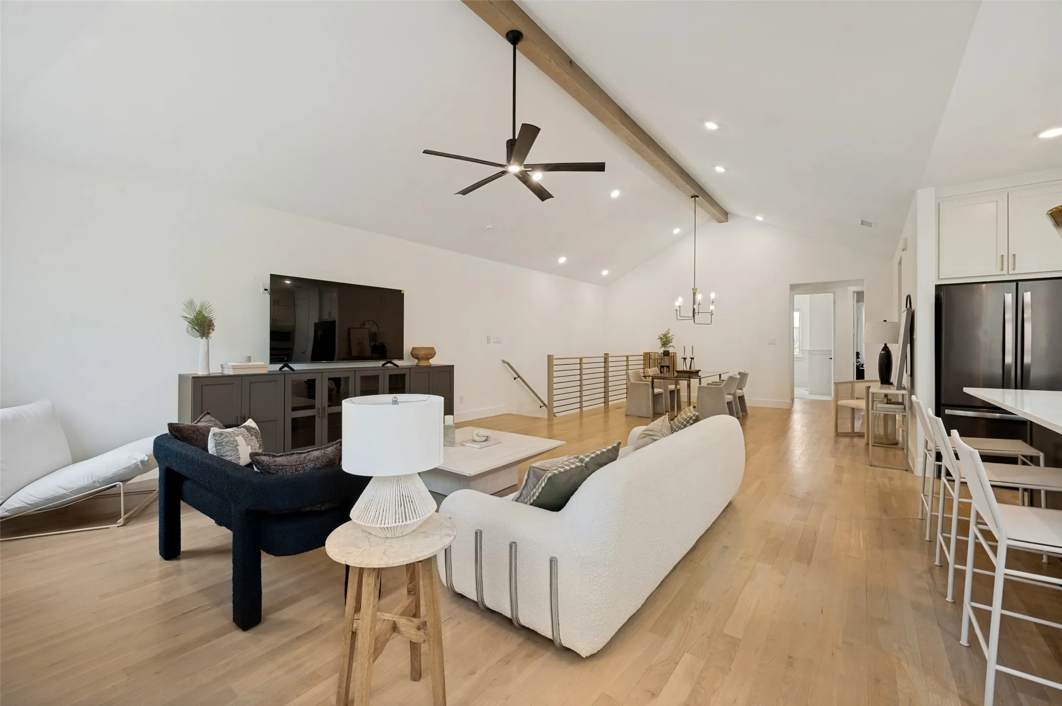 Vaulted ceiling with exposed wood beam, wood-finish flooring, recessed lighting, and a modern ceiling fan