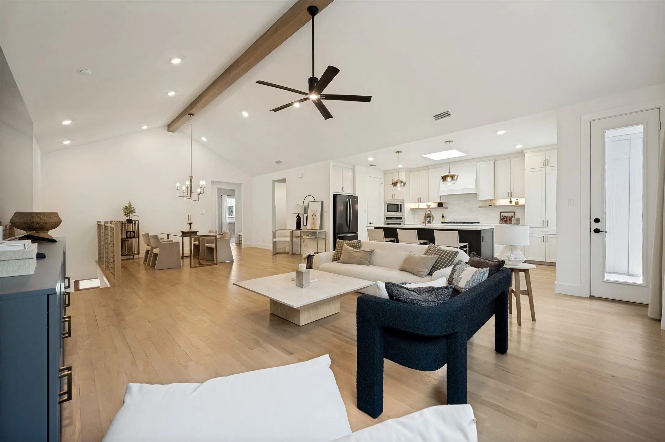 Vaulted ceilings with exposed beam, recessed lighting, and wood-finish flooring