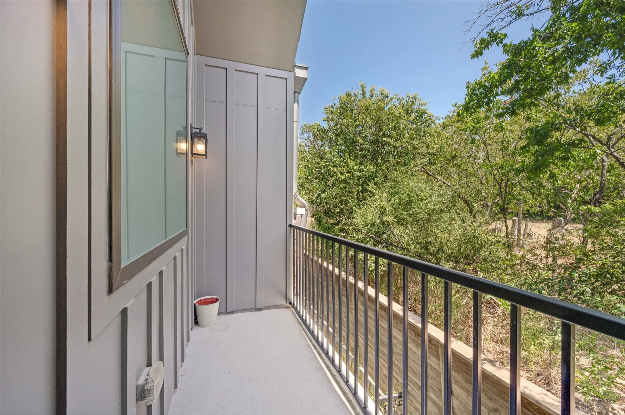 Outdoor balcony featuring a black metal railing and a wall-mounted exterior light fixture