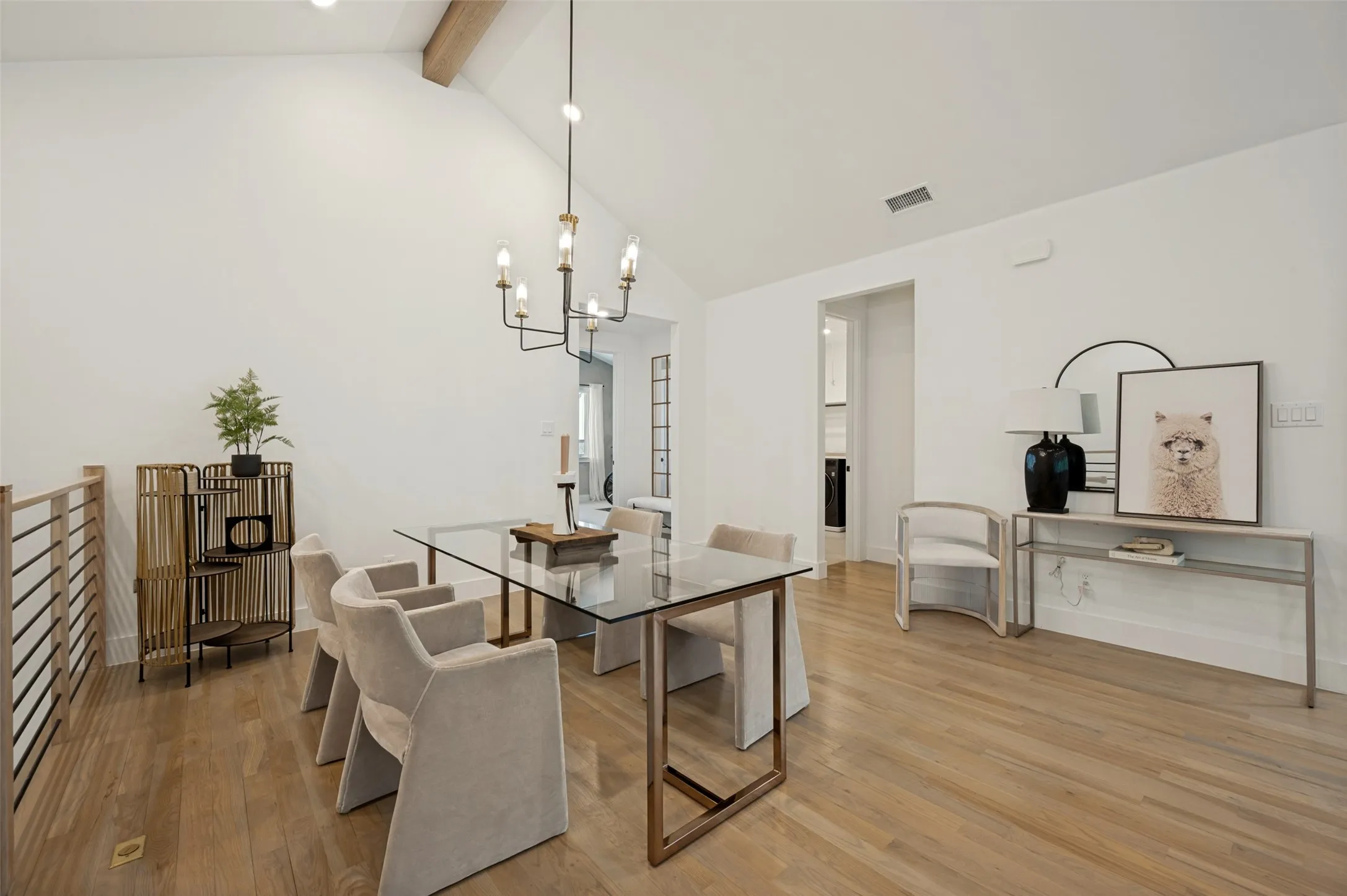 Vaulted ceiling with an exposed wood beam, wood-finish flooring, and a modern chandelier