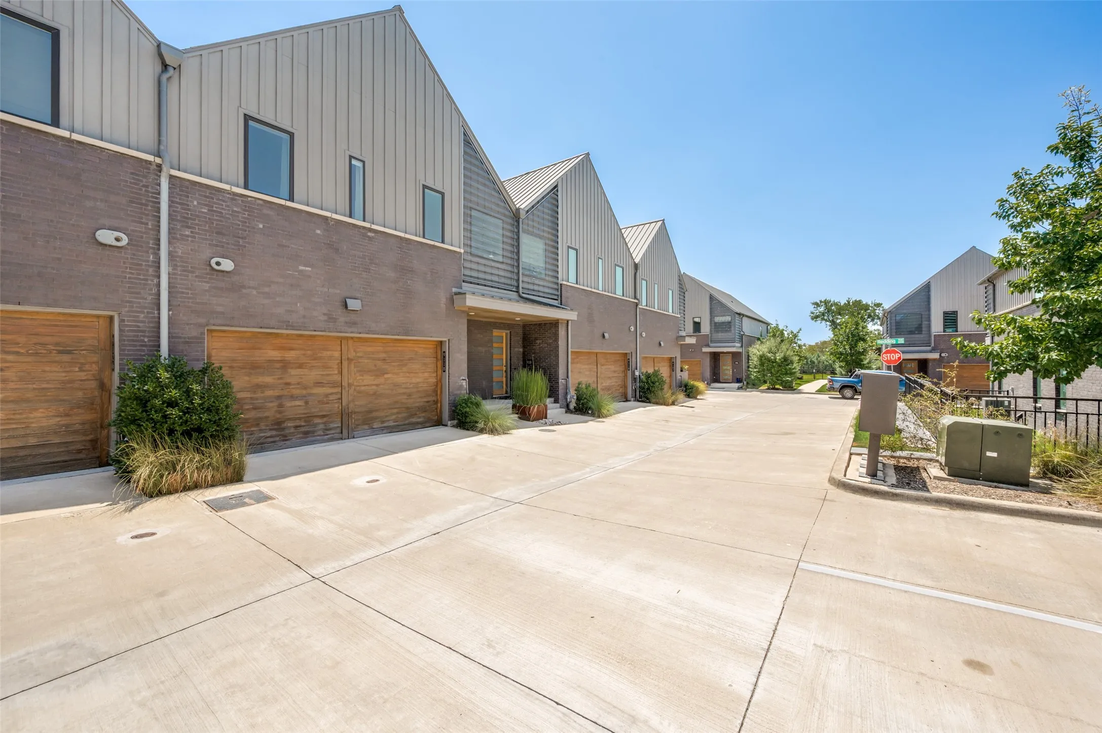 Modern architectural design featuring vertical metal siding, brick facade, and wood-finish garage doors