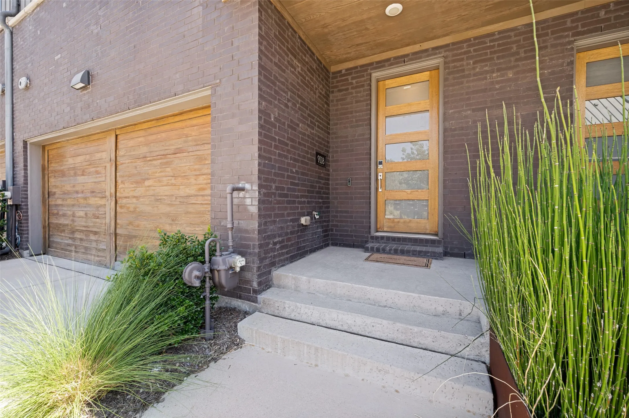 Brick exterior with a contemporary wood door featuring frosted glass panels