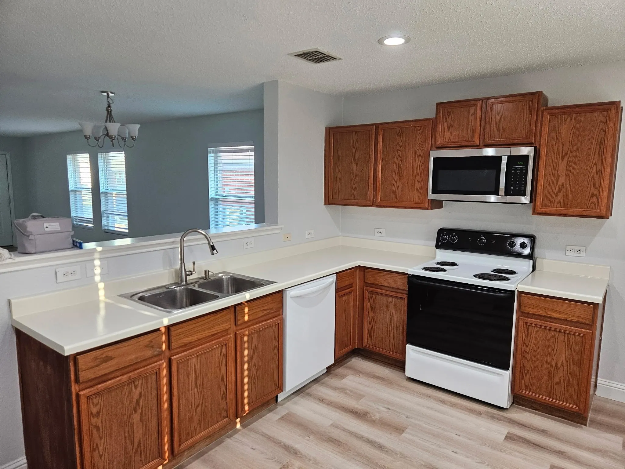 Kitchen featuring wood-finish cabinetry, light-toned countertops, and a dual basin stainless steel sink