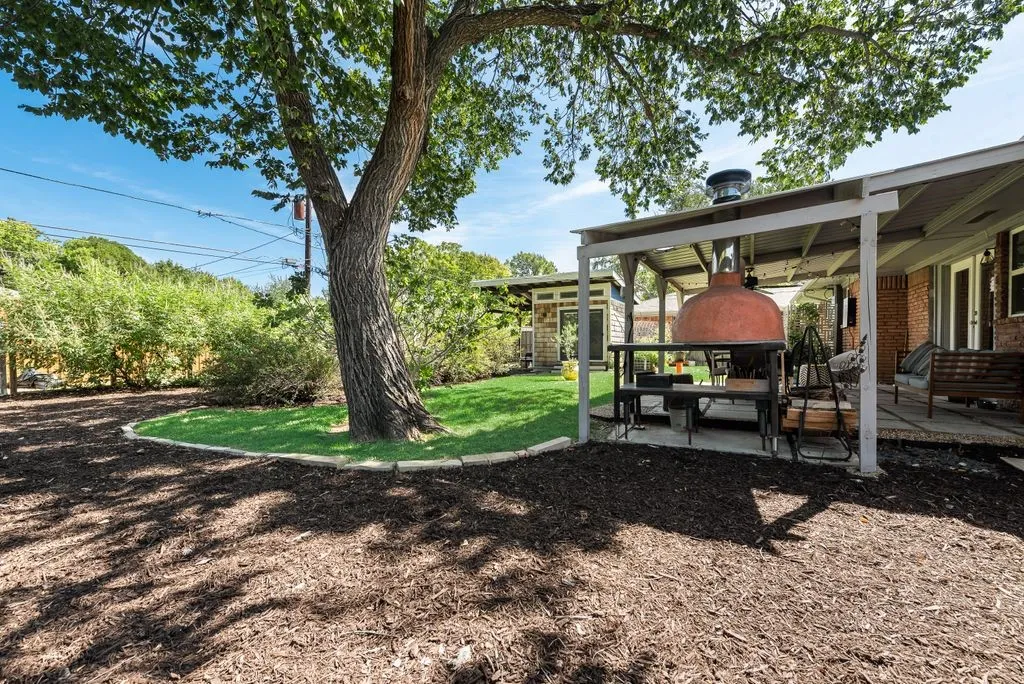 This backyard was built to host get-togethers - covered patio, pizza oven and room for pets and kids to play.