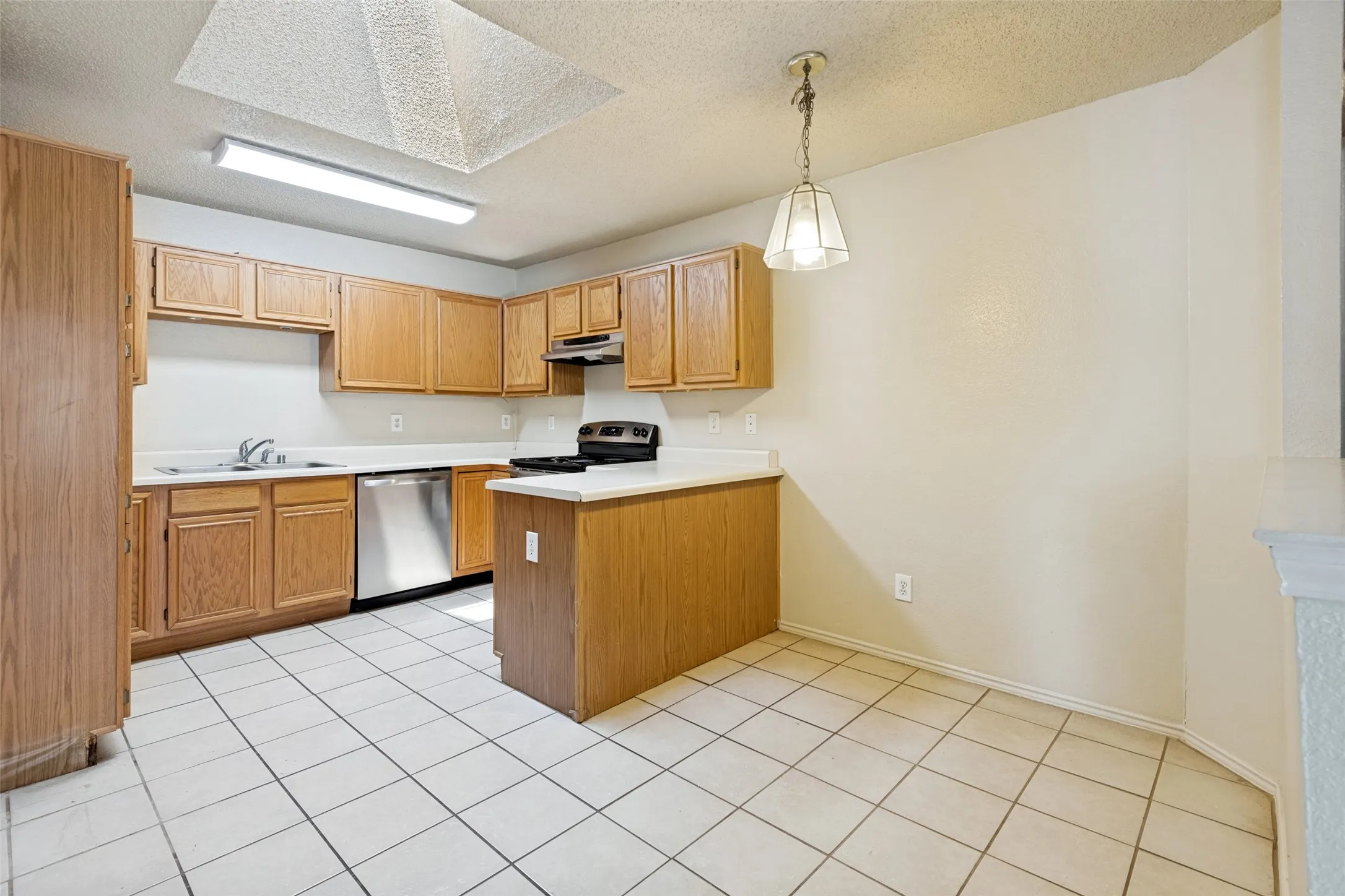 Kitchen featuring wood-finish cabinetry, white countertops, a stainless steel dishwasher, and a black range