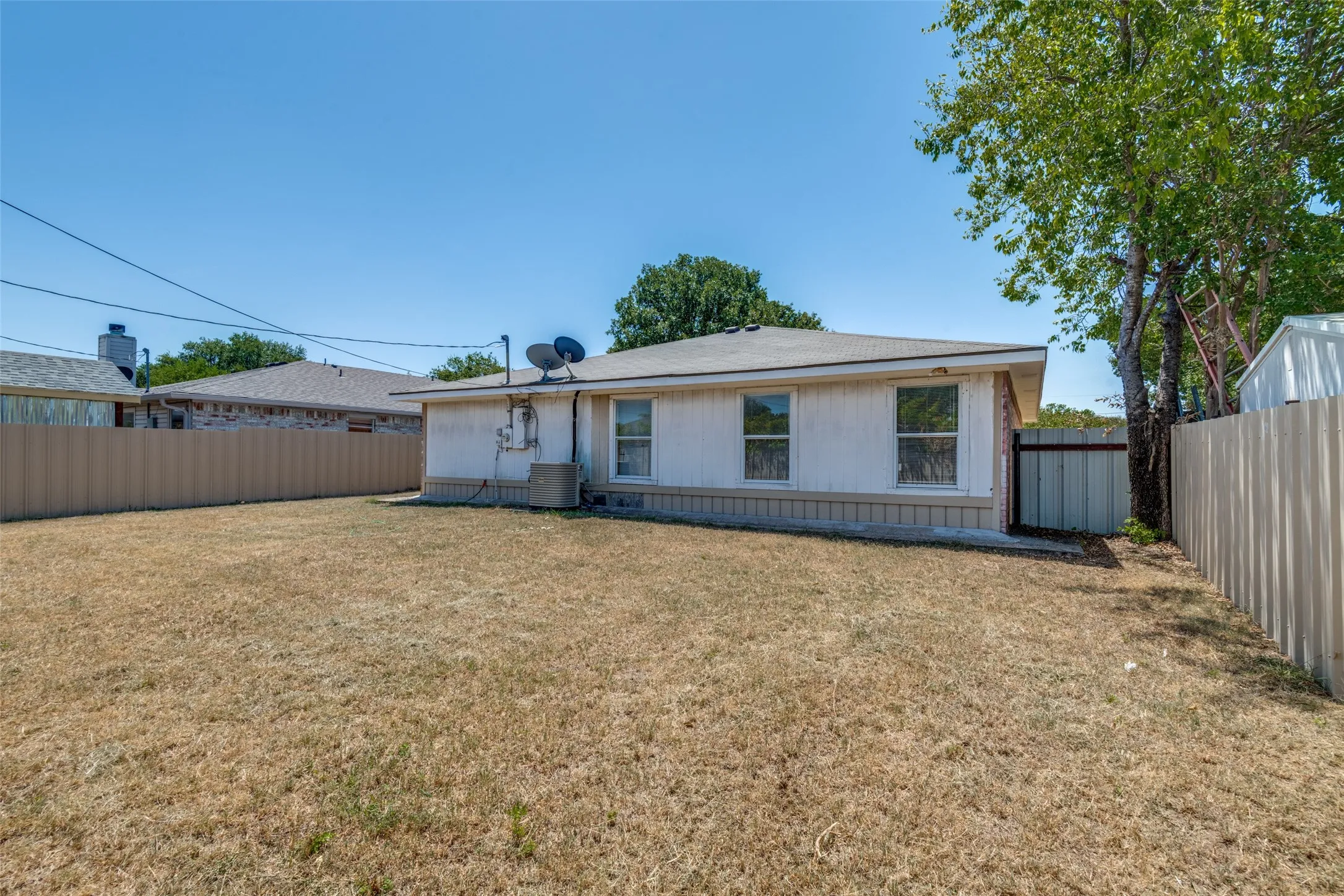 Expansive backyard with a metal privacy fence and mature trees