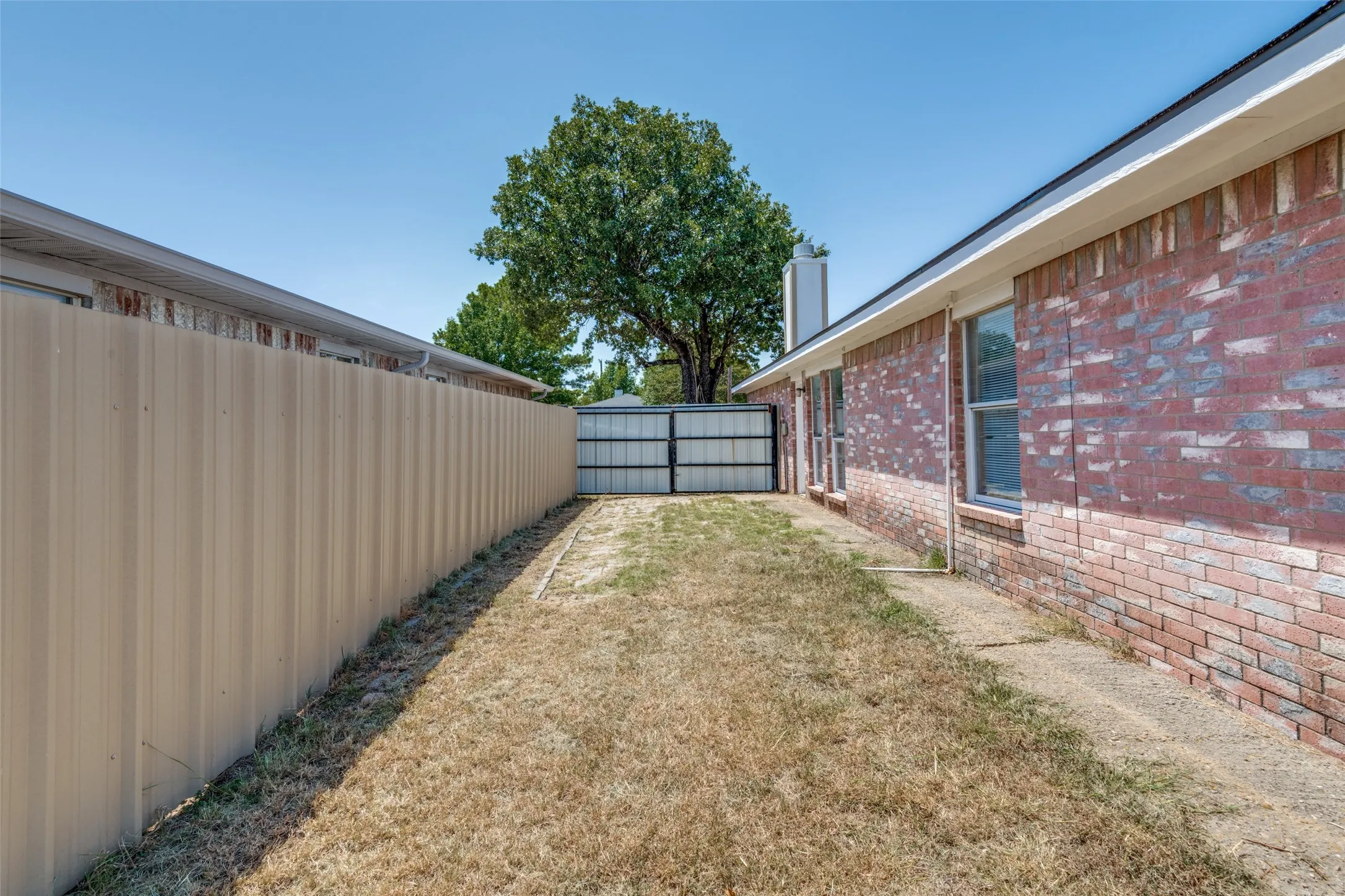 Brick exterior, metal privacy fence, and concrete walkway