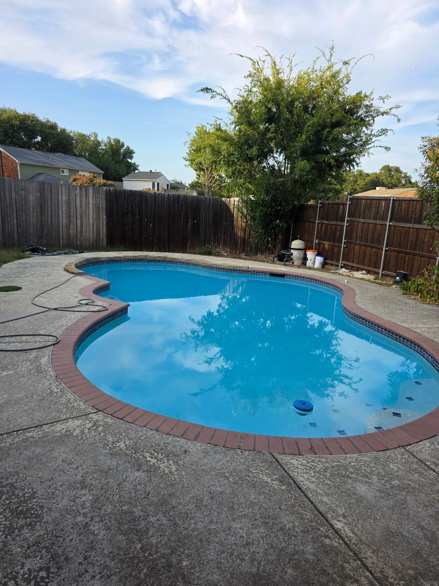 In-ground swimming pool with brick coping and concrete surround