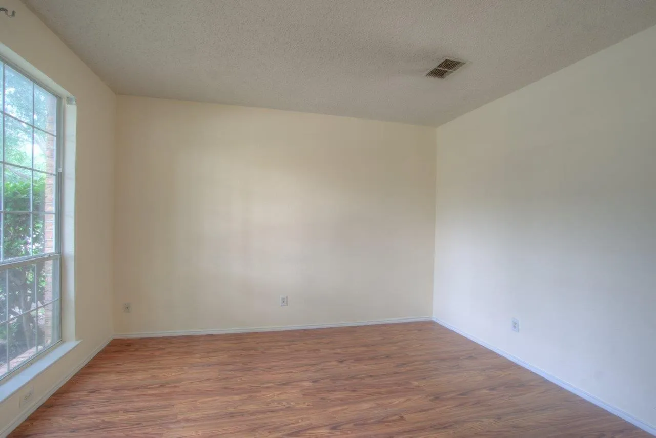 Window with grid pattern, wood-finish flooring, light-toned walls, and recessed lighting