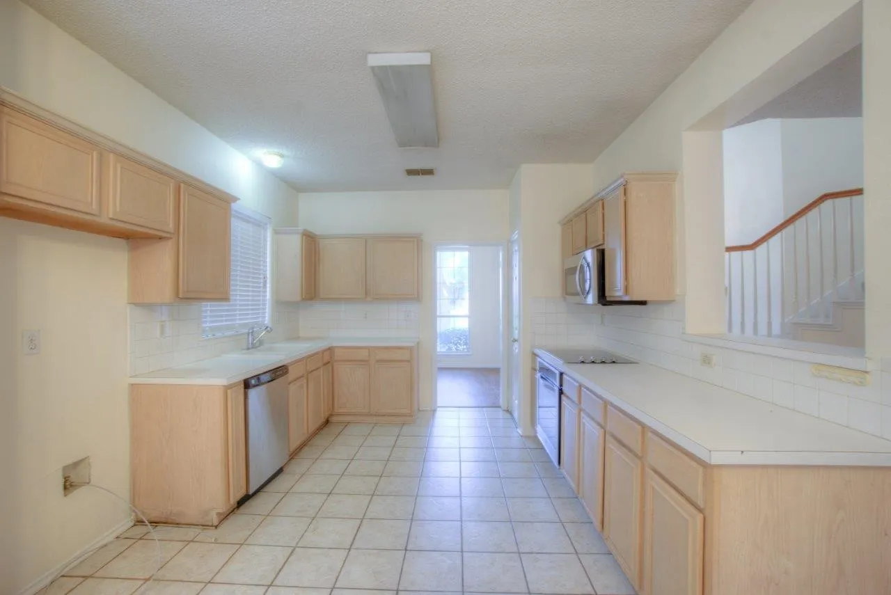 Expansive kitchen featuring light wood cabinetry, white tile flooring, white countertops, and white subway tile backsplash