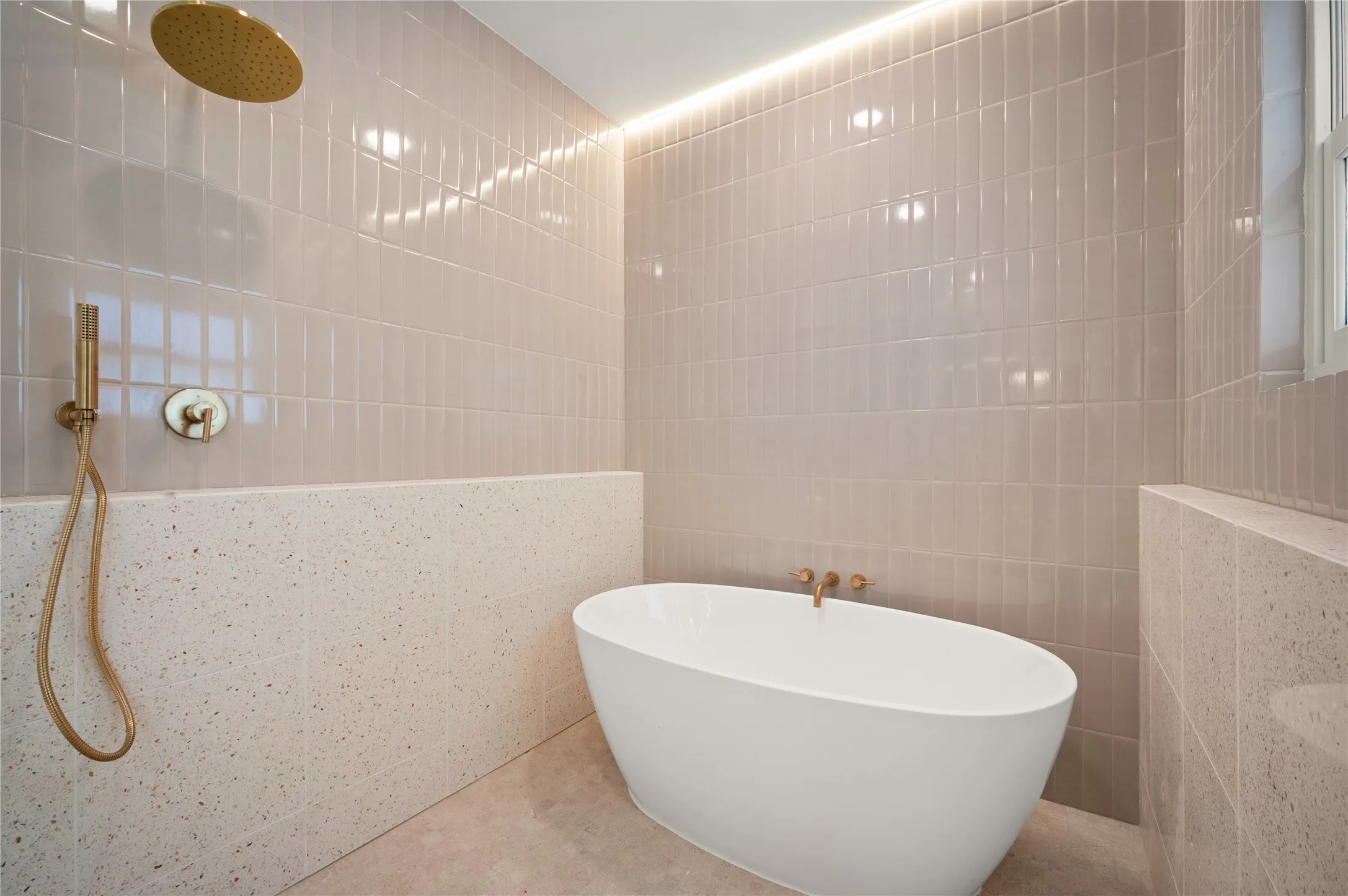 Natural light enhances the floor-to-ceiling vertical tile, decorative ceiling lighting, and gold-finish fixtures
