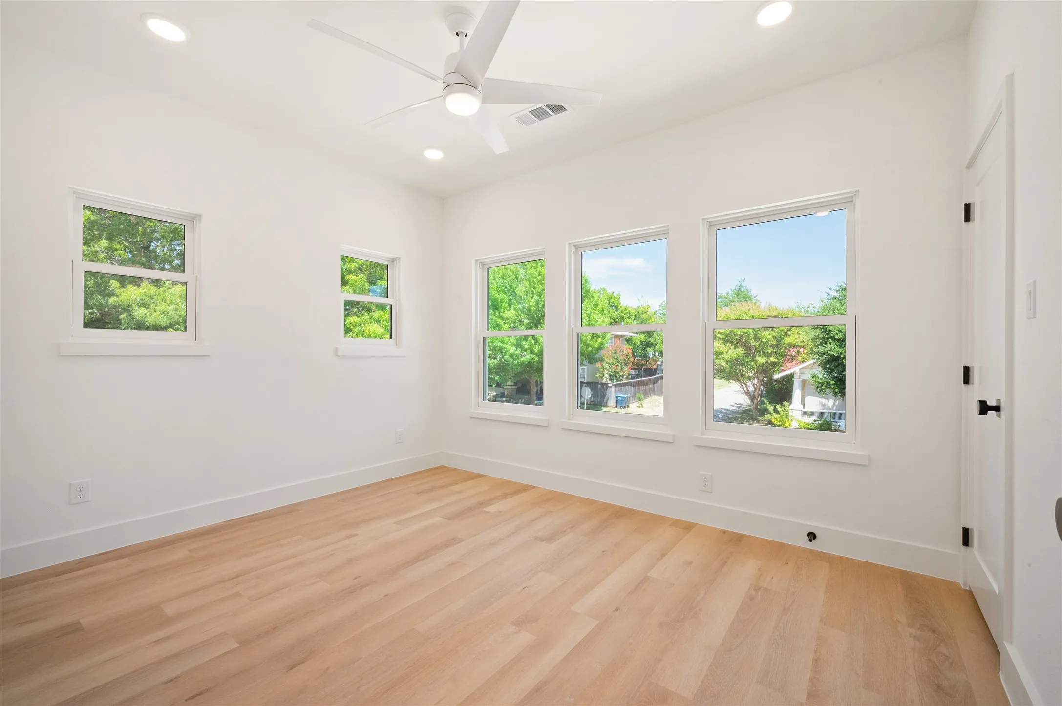 Second floor bedroom with dual closets, Light wood-finish flooring, ceiling fan, and multiple windows