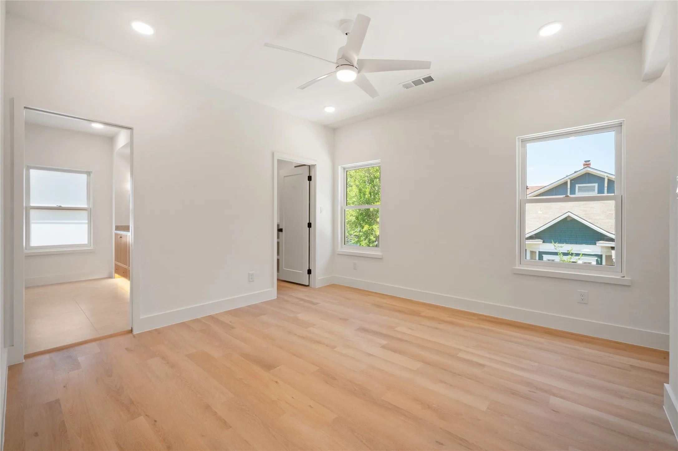Vaulted ceiling with a flush-mount ceiling fan, recessed lighting, wood-finish flooring, and white trim throughout