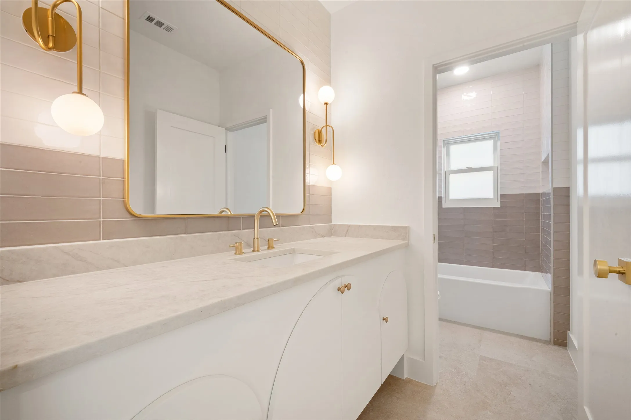 Upstairs bathroom. White vanity with integrated sink, gold-finish faucet, and coordinating wall sconces