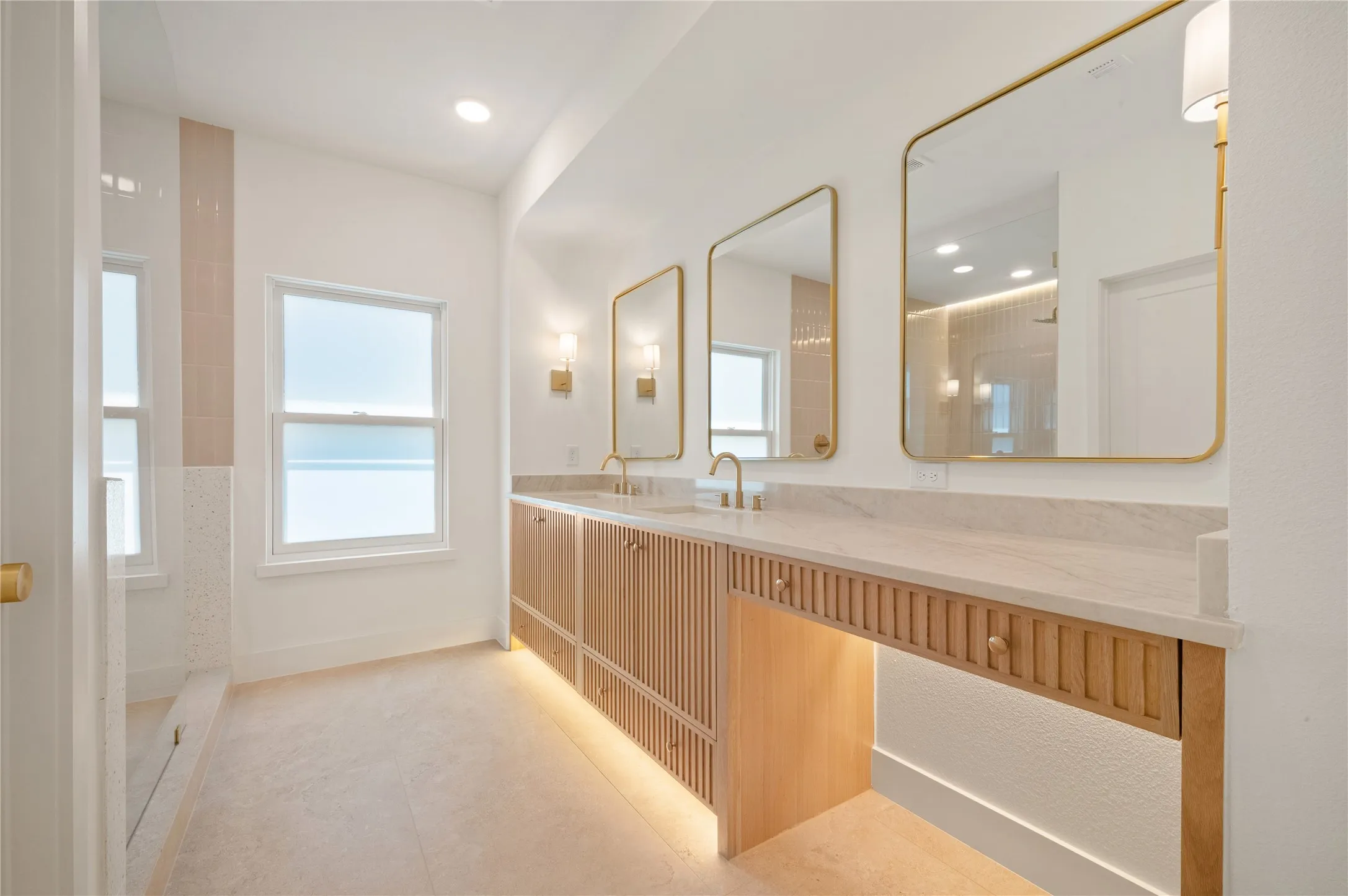 Large framed mirrors, and under-cabinet lighting accent this primary bathroom