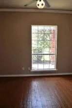Wood-finish flooring with a satin sheen and a ceiling fan with integrated lighting