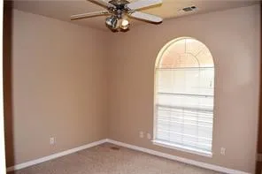 Arched window with blinds, ceiling fan with light fixture, carpeted flooring, and neutral wall tones