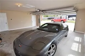 Attached garage with a roll-up door, concrete flooring, and interior access doors