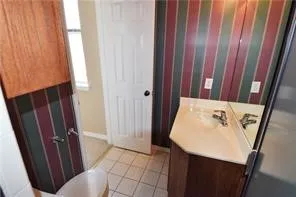Dual vanity with integrated sinks, wood-finish cabinetry, and tiled flooring