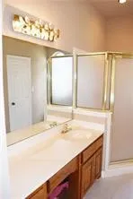Double vanity with integrated sink, wood-finish cabinetry, and full-width mirror