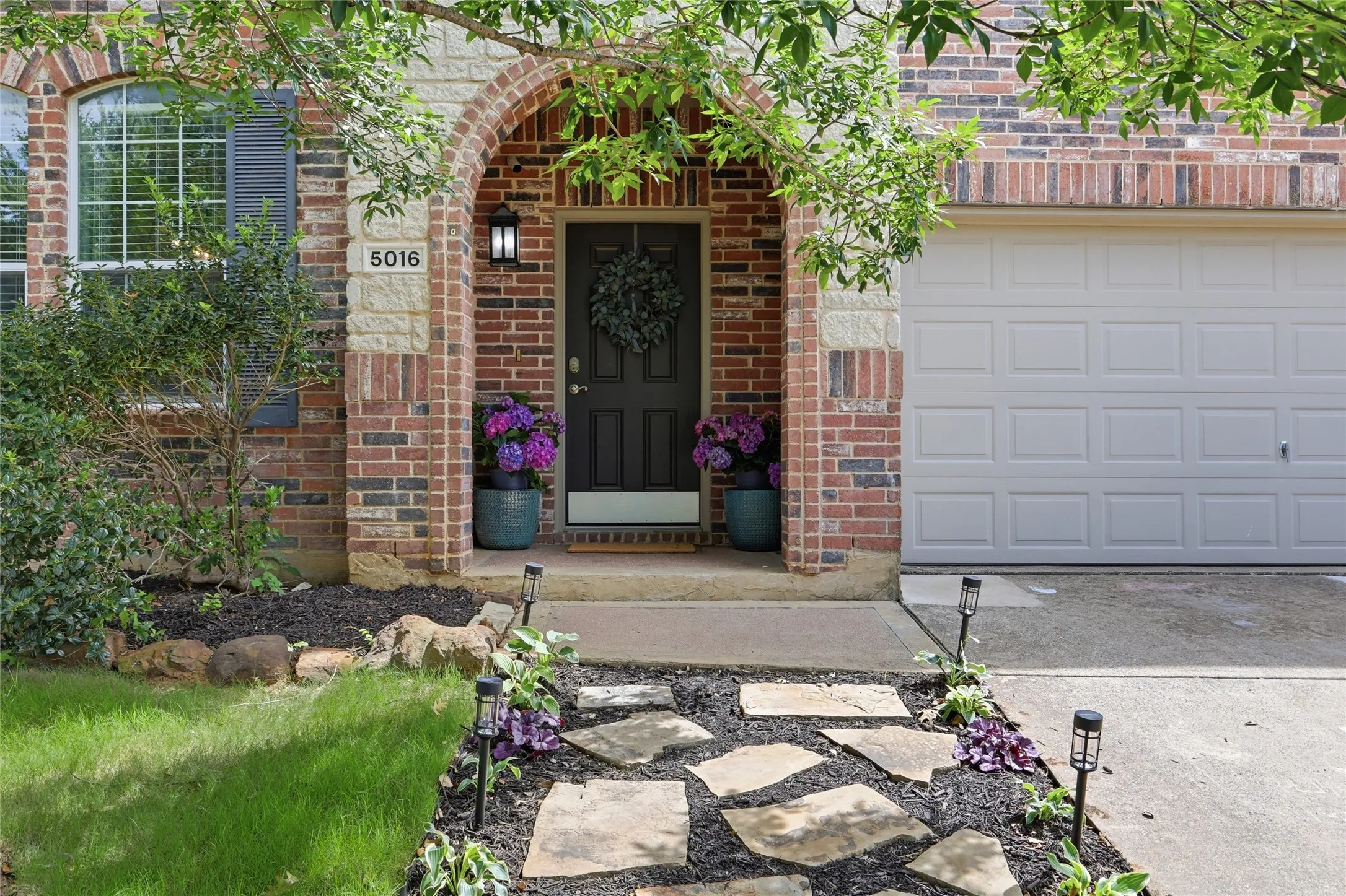 Brick and stone veneer exterior featuring an arched entryway