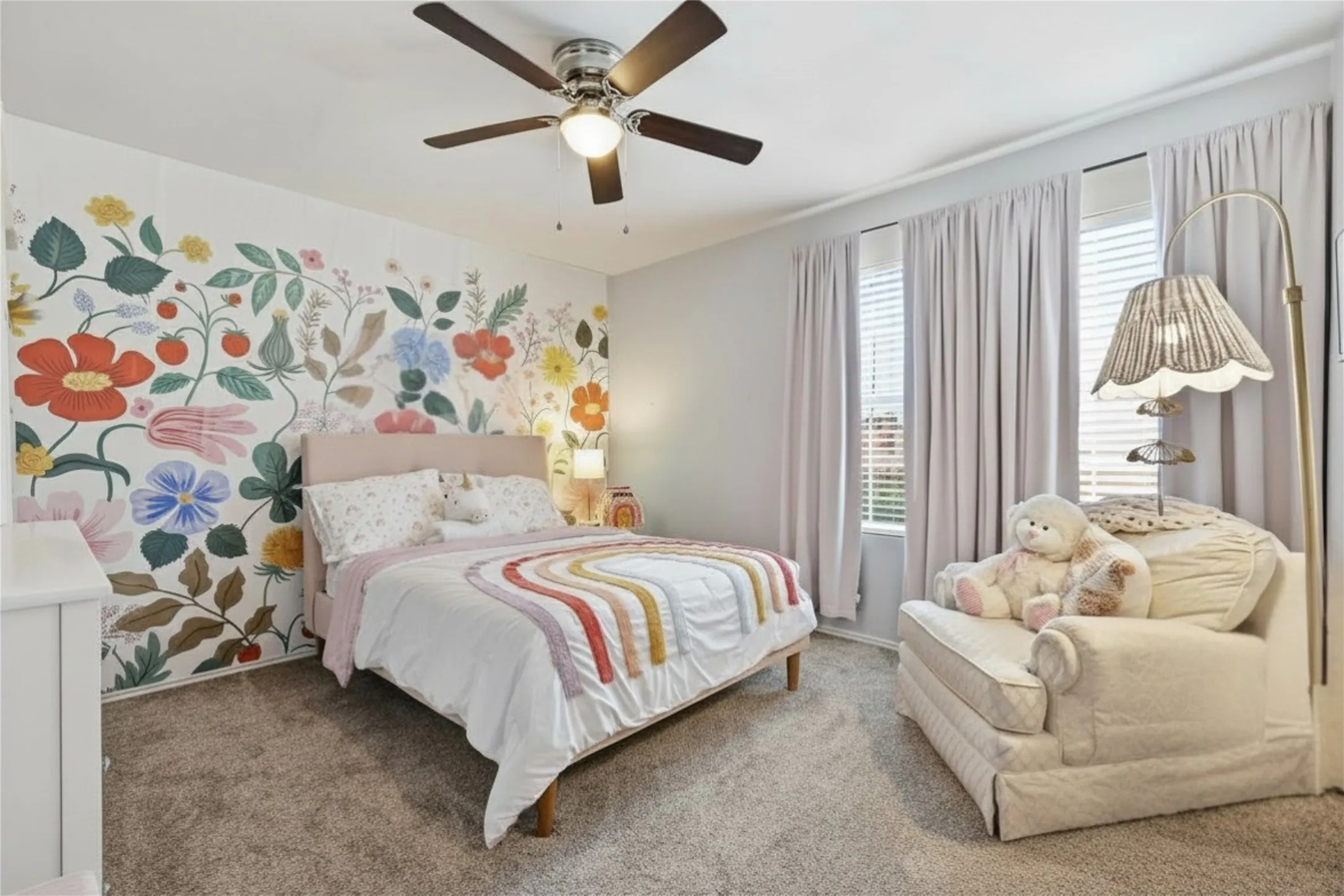 Bedroom featuring a decorative floral accent wall, ceiling fan with integrated lighting, and carpeted flooring
