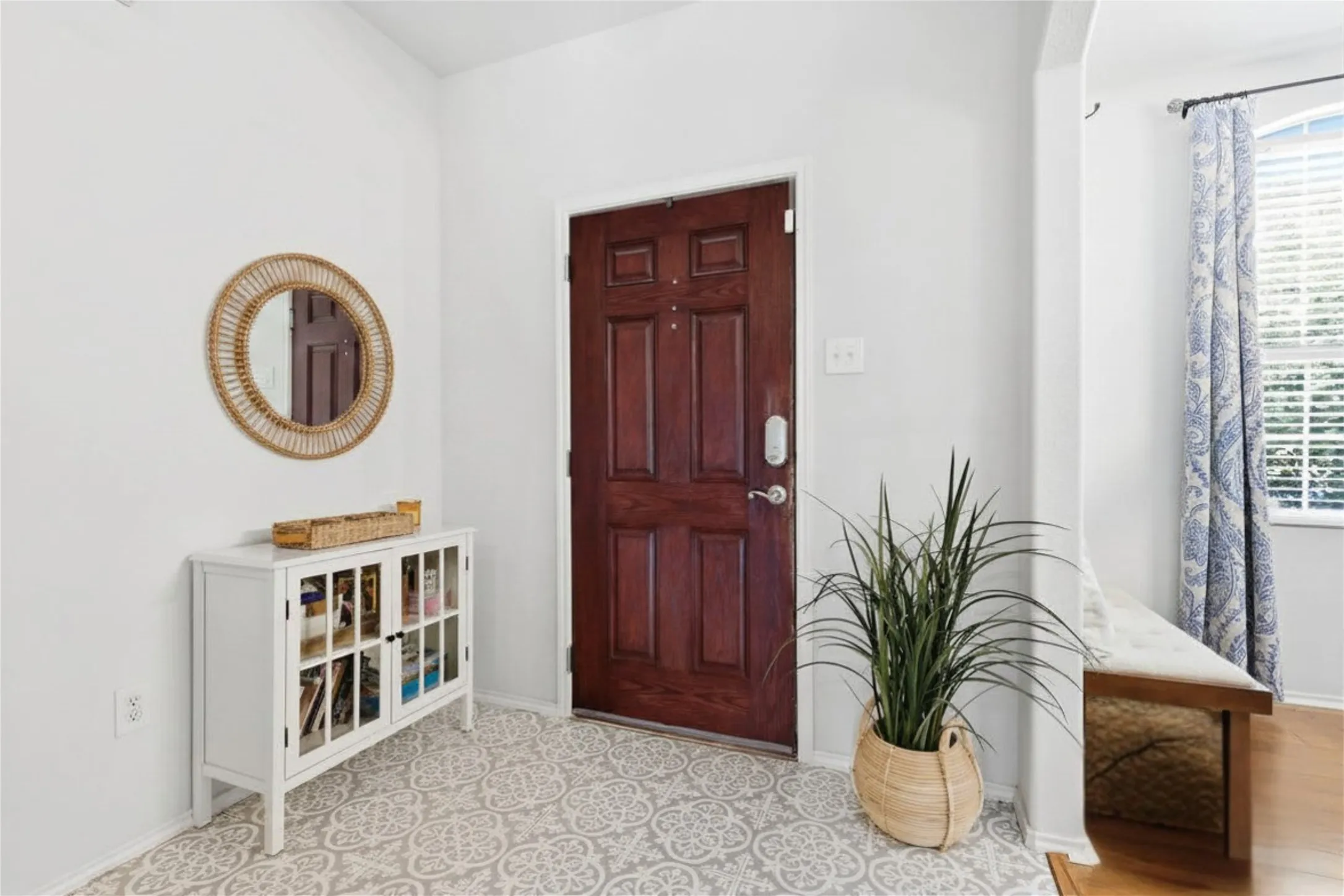 Entryway featuring a rich wood-paneled door, patterned tile flooring, and crisp white walls