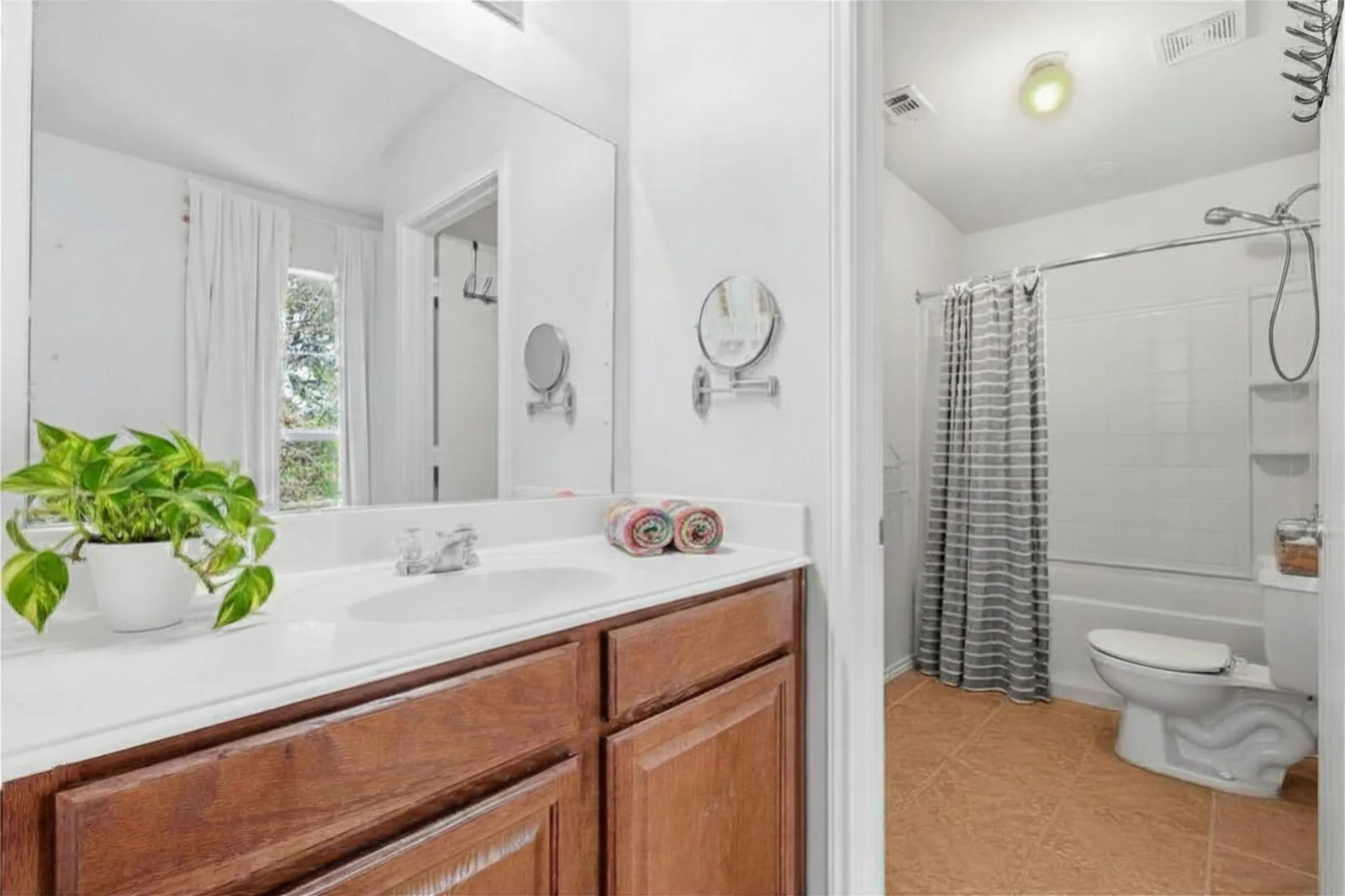 Bathroom featuring a wood-finish vanity with a white countertop, an integrated sink, and a large mirror
