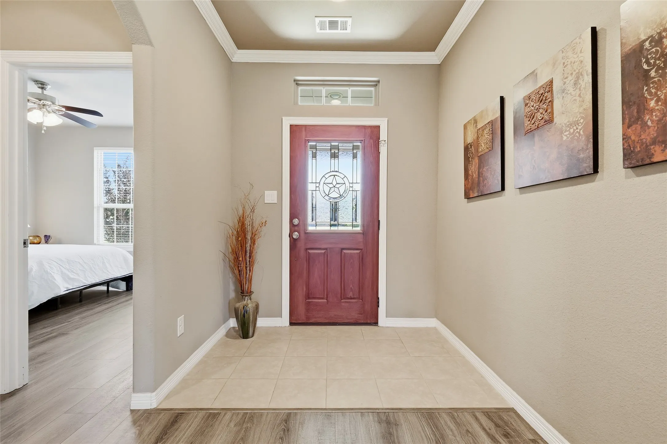 Entryway featuring a decorative transom window, recessed ceiling detail, and crown molding