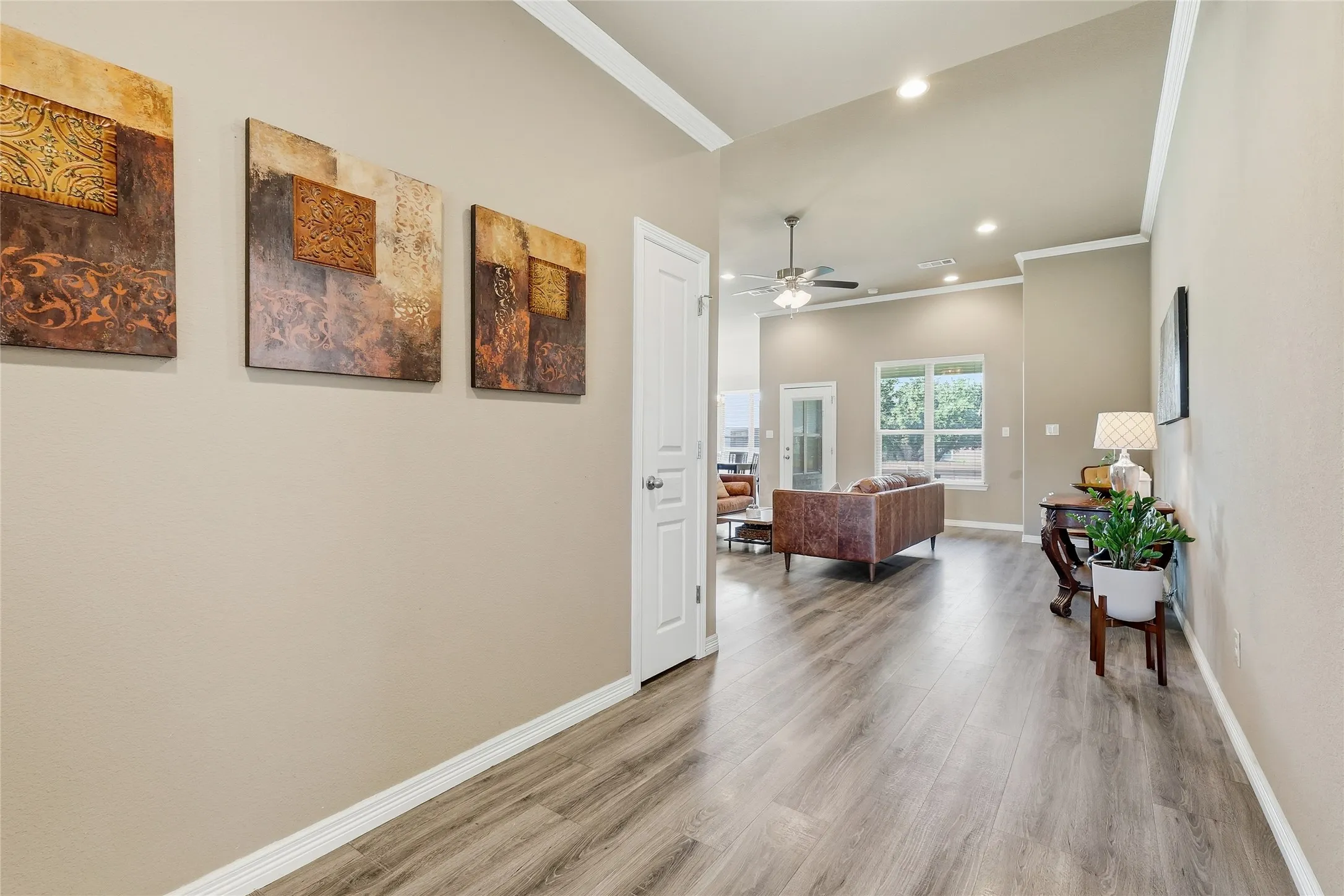 Hallway featuring wood-finish flooring, neutral wall paint, white trim, and a high ceiling