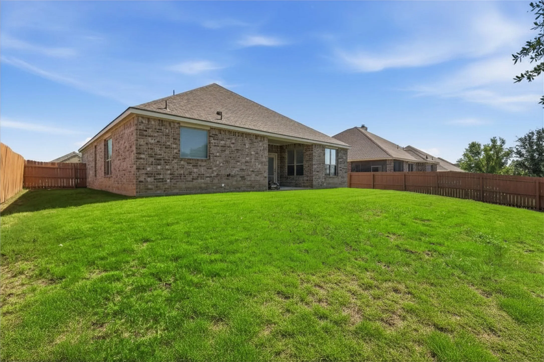 Expansive green lawn with a privacy fence bordering the property