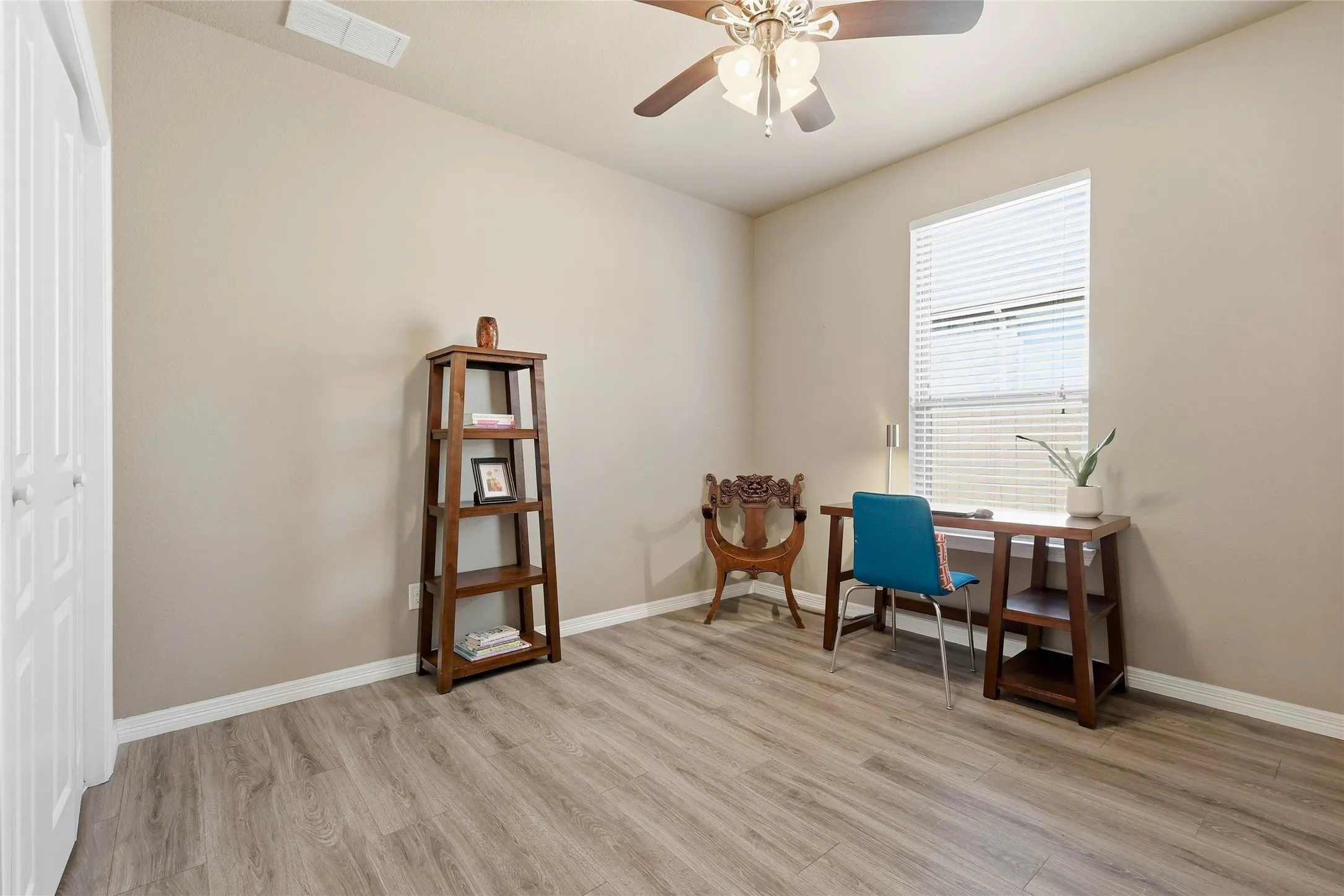 Room featuring wood-finish flooring, neutral wall tones, and a ceiling fan with integrated lighting