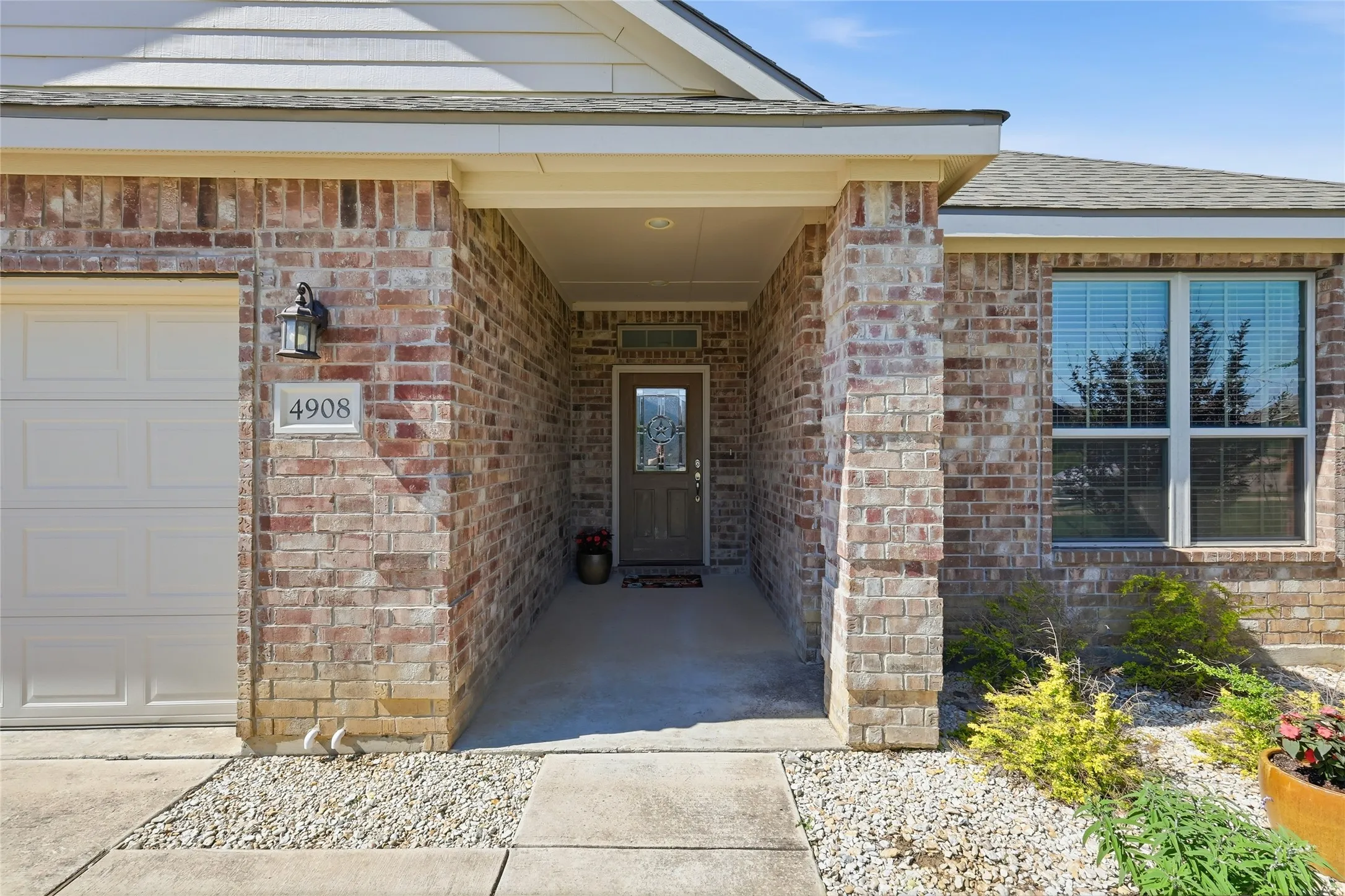 Brick exterior featuring a covered entry, an integrated garage, and a transom window above the front door