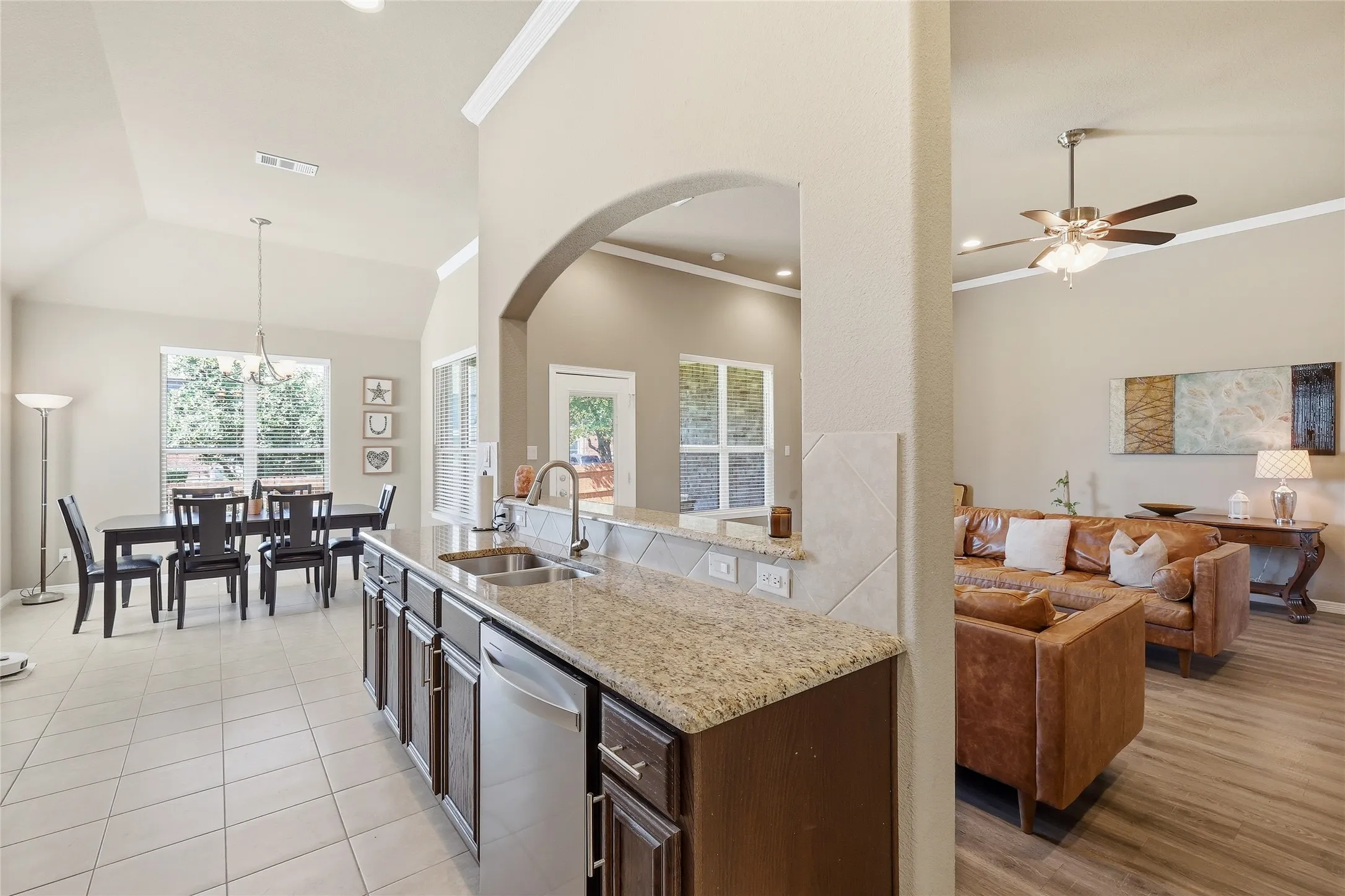 Kitchen island with granite-finish countertop, stainless steel double sink, and dark wood cabinetry