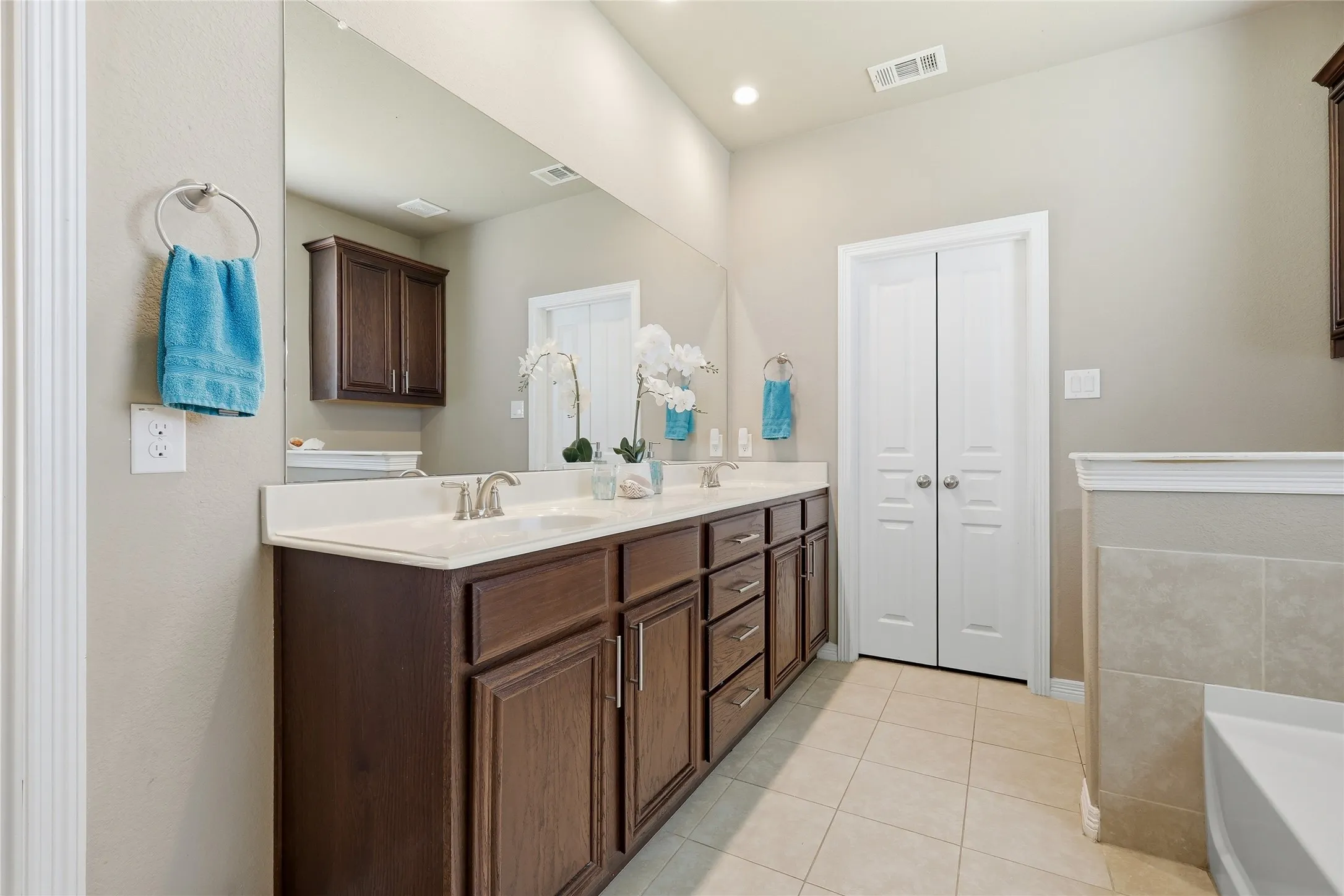 Bathroom featuring a dual vanity with dark wood-finish cabinetry, light-toned countertop, and undermount sinks