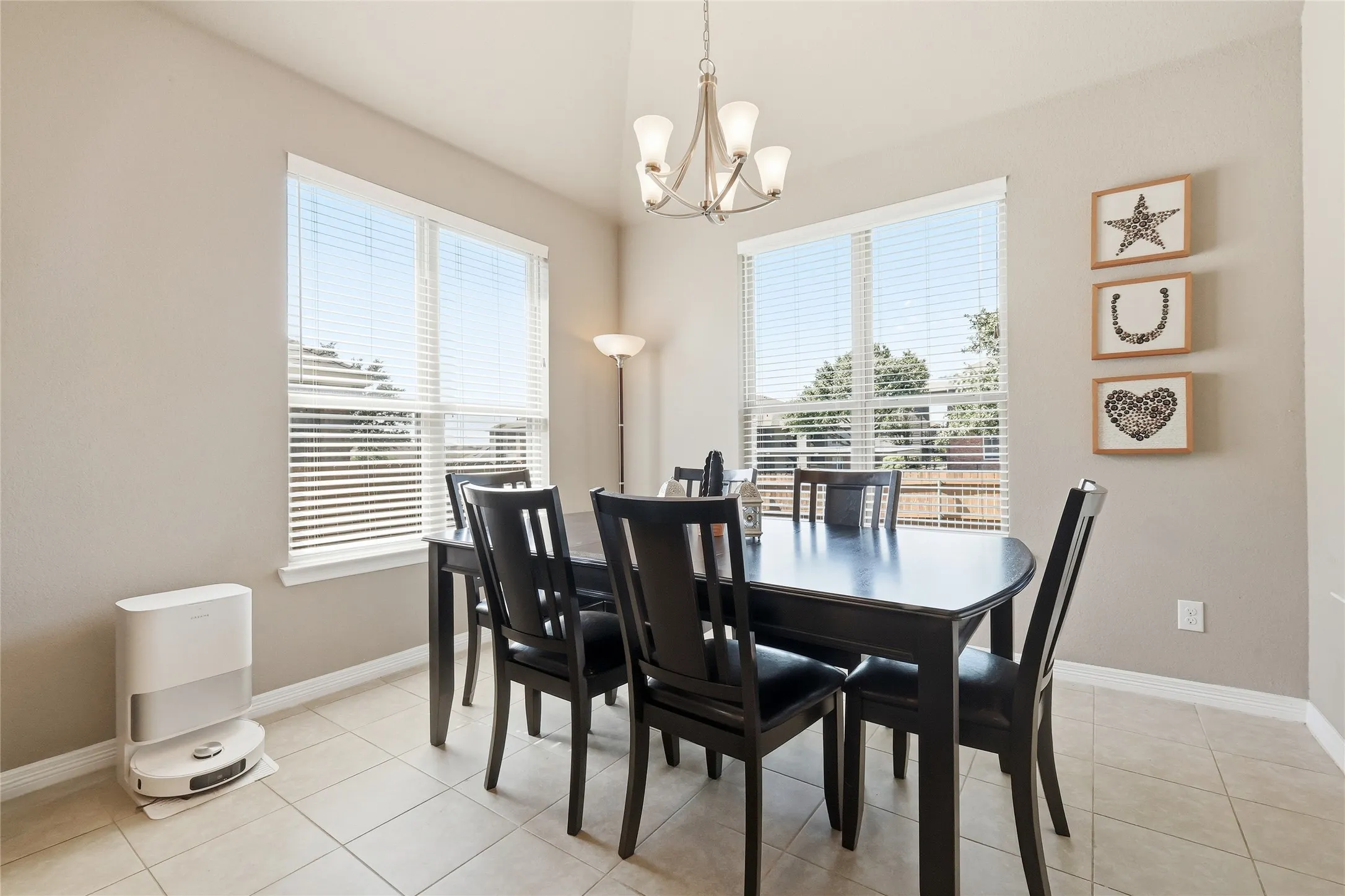 Dining space featuring two large windows with blinds, a vaulted ceiling, and a five-light chandelier