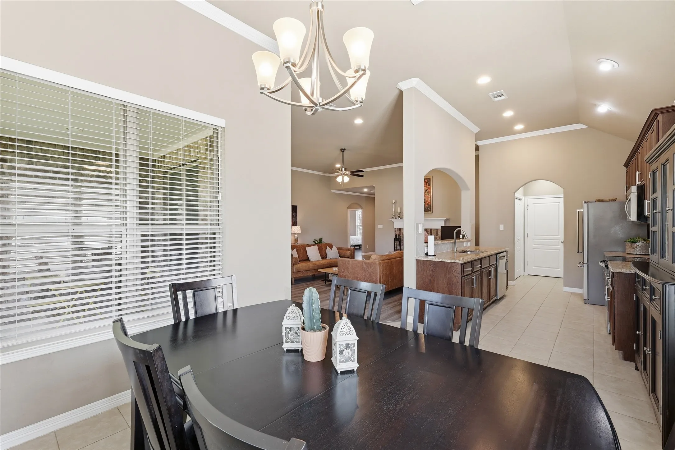 Dining area featuring a vaulted ceiling, transom window with blinds, and a contemporary chandelier