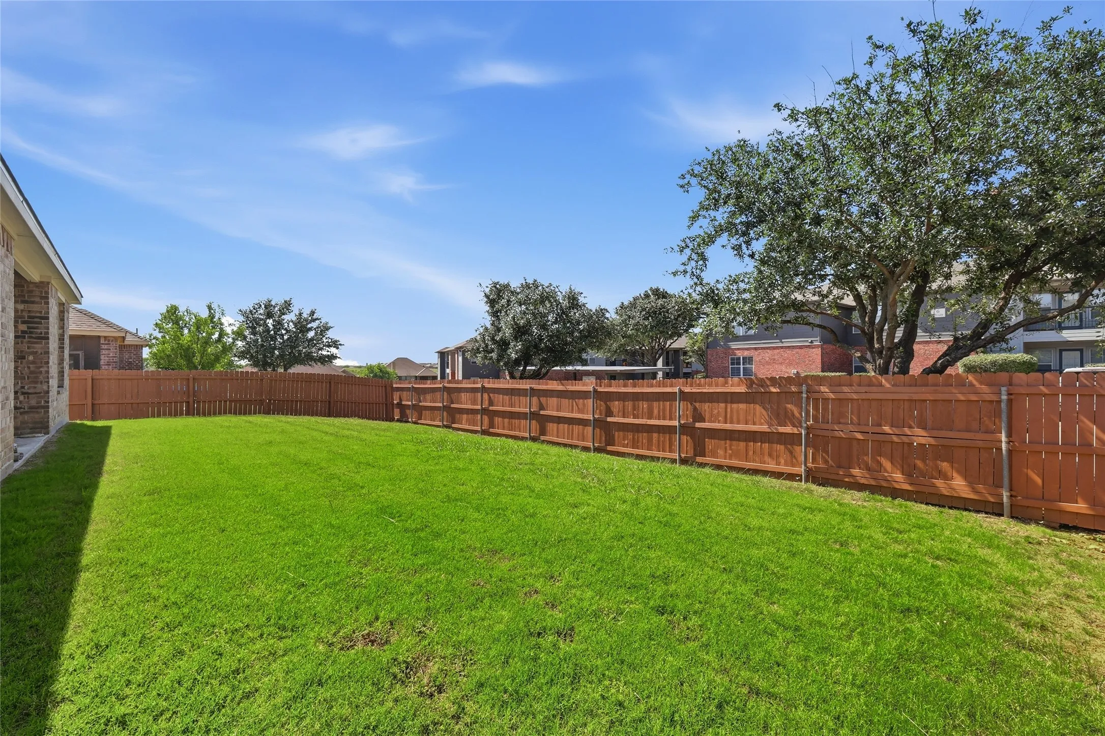 Expansive backyard featuring a lush green lawn and mature trees